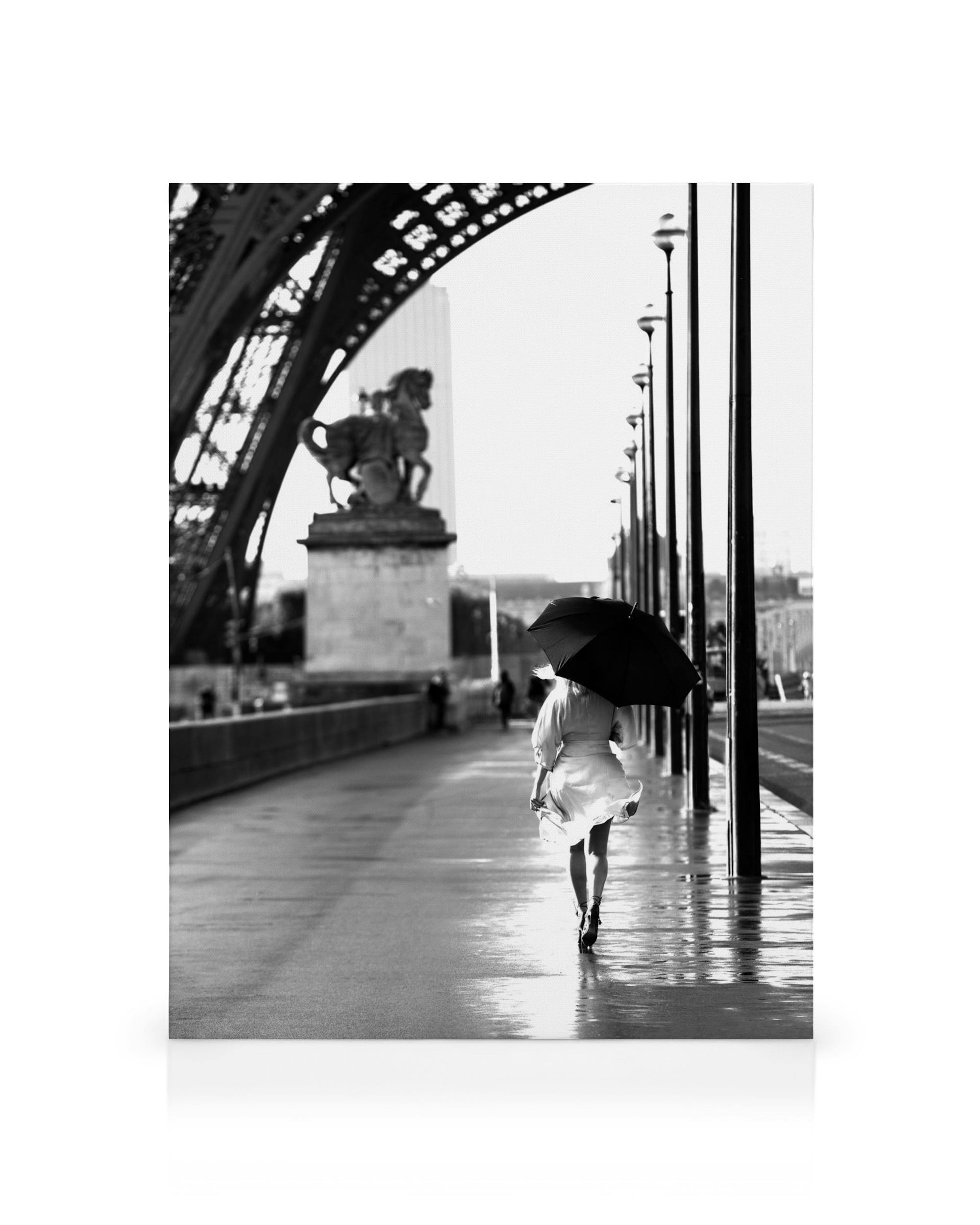 Zwart-wit canvas van een persoon met paraplu op natte stoep in Parijs, weerspiegeling op de grond