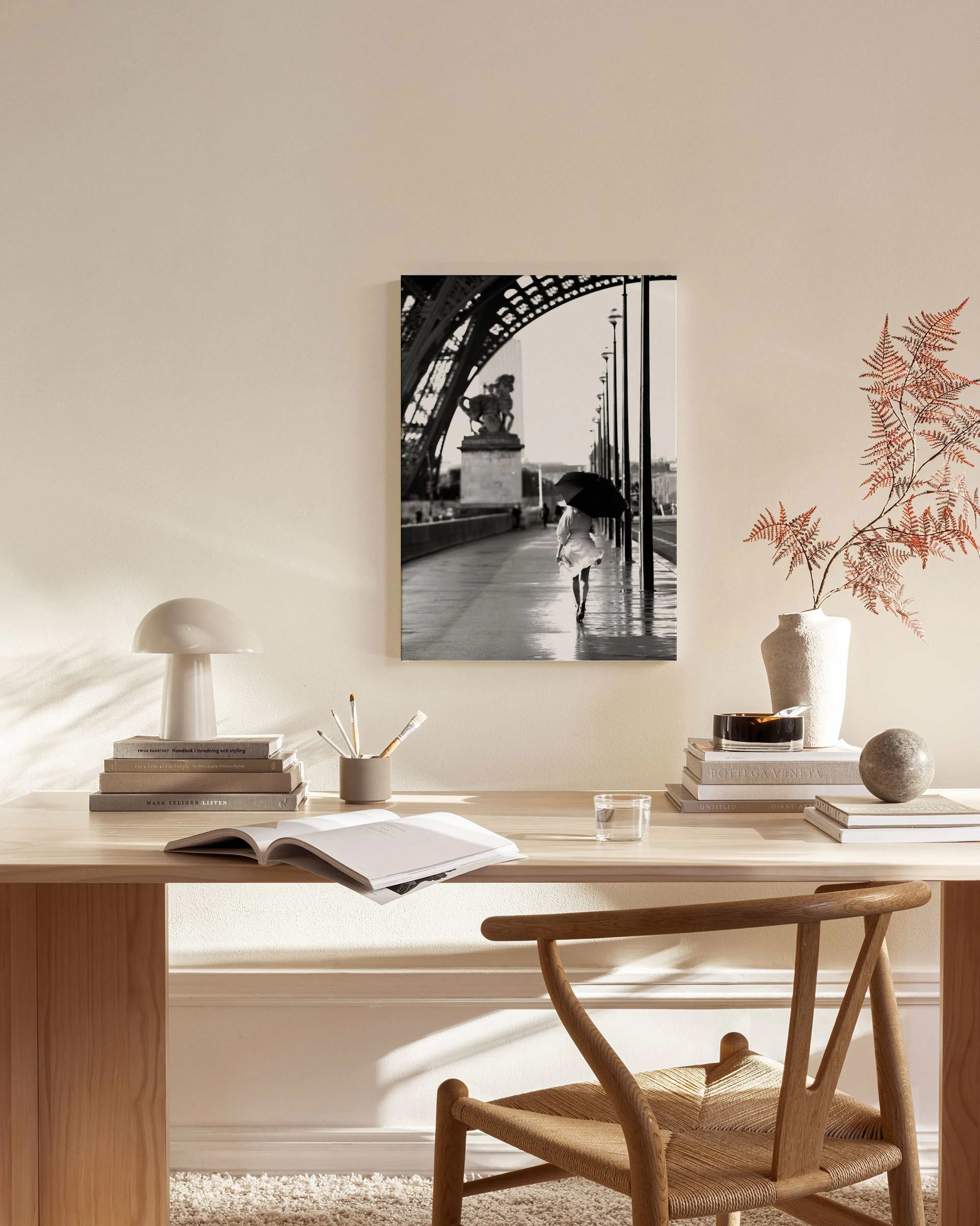 Black and white canvas print of a person with an umbrella on a wet bridge, displayed in a modern living room.