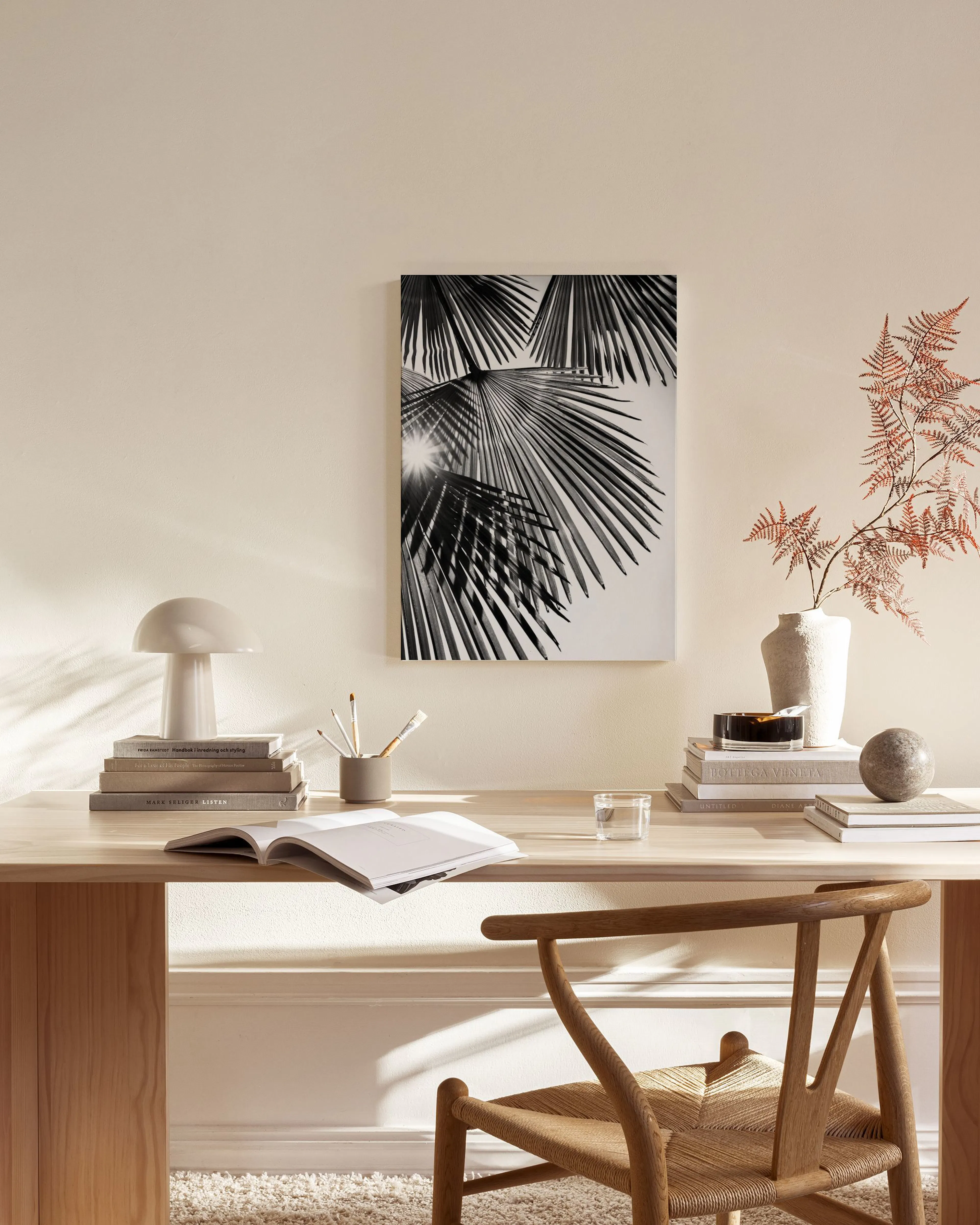Black and white canvas print of palm leaves with sun flare, hanging in a bright, minimalist living room.