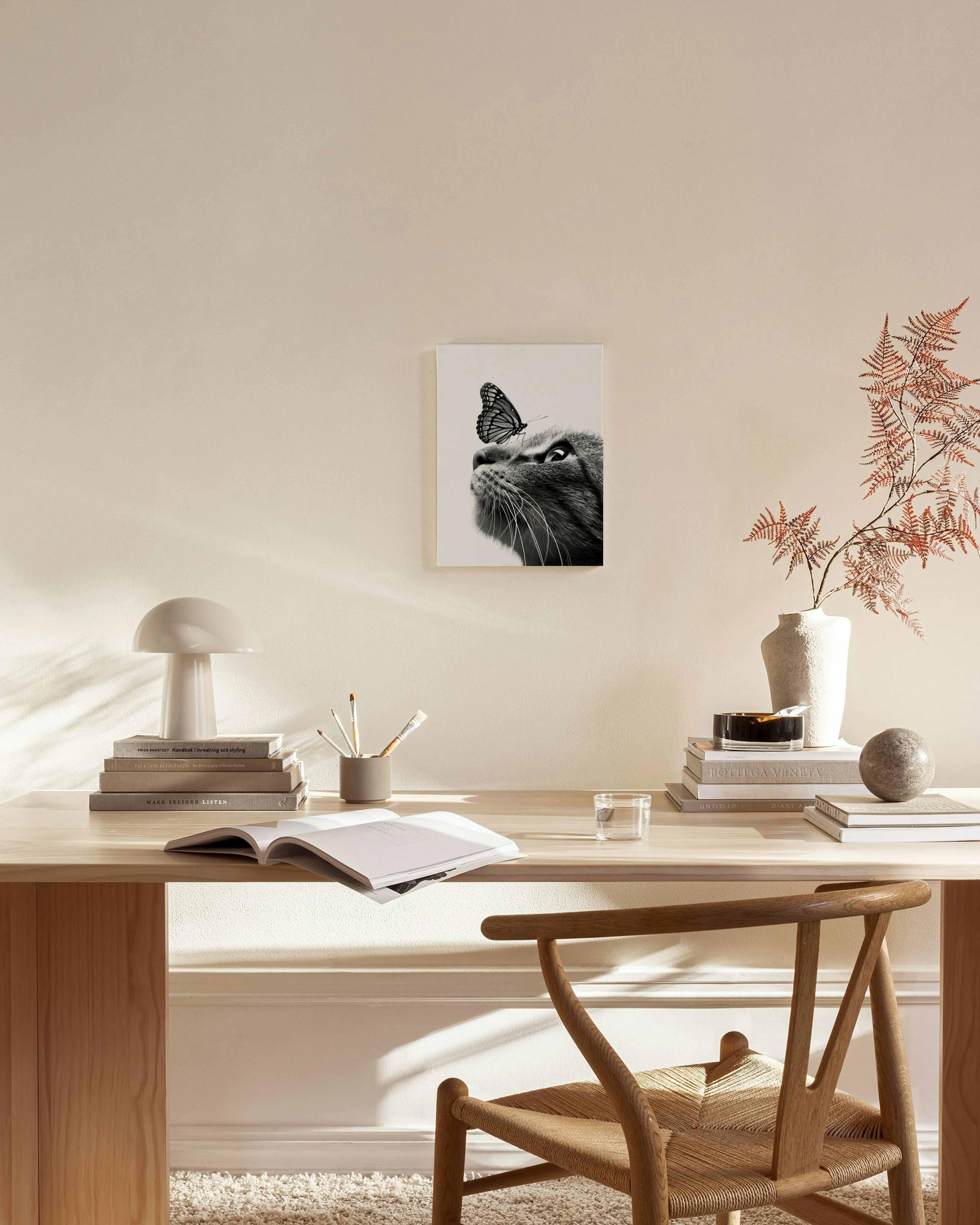 Black and white canvas print of a cat looking up at a butterfly, displayed in a minimal living room.