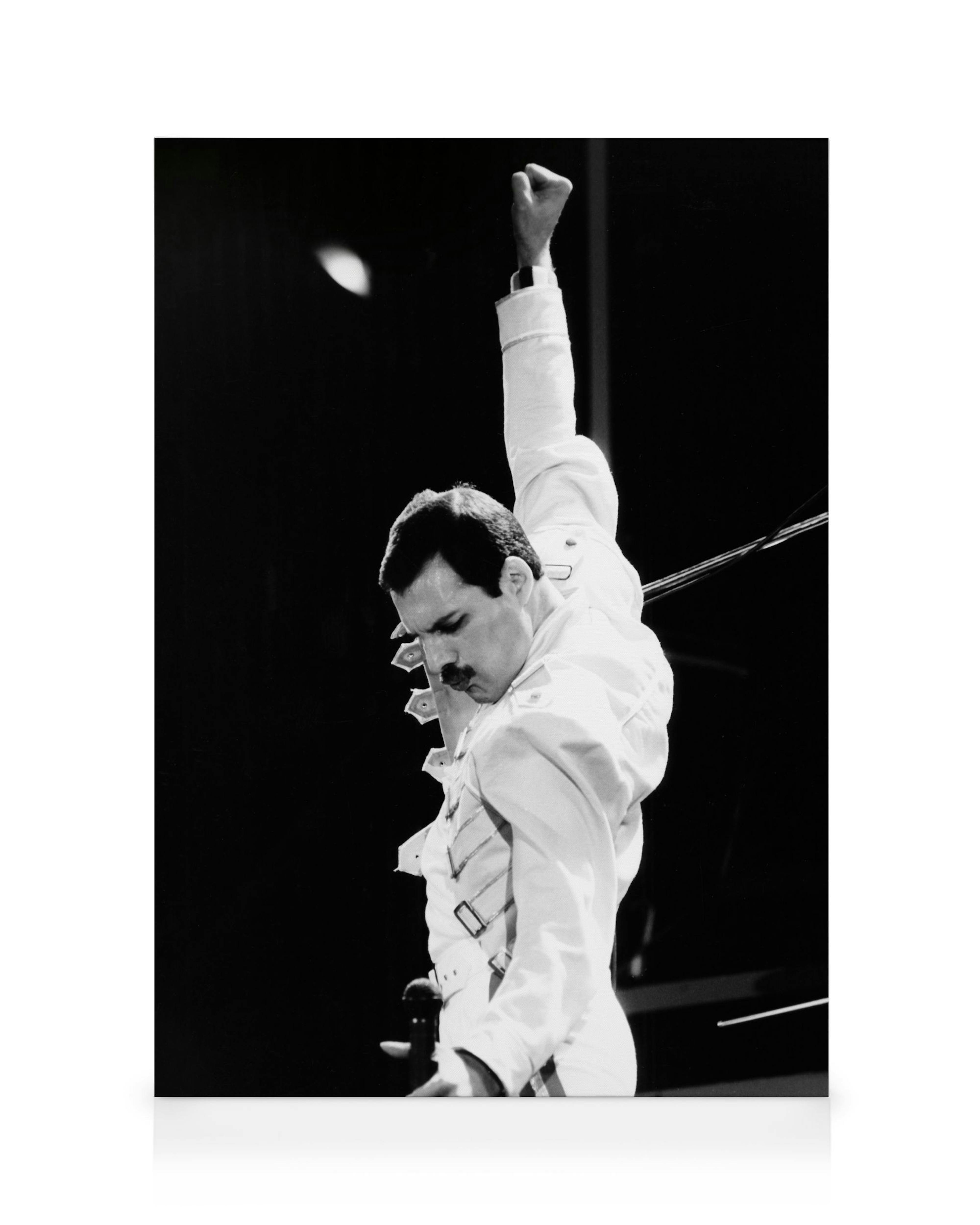 A black and white canvas print of Freddie Mercury with his right arm triumphantly raised.