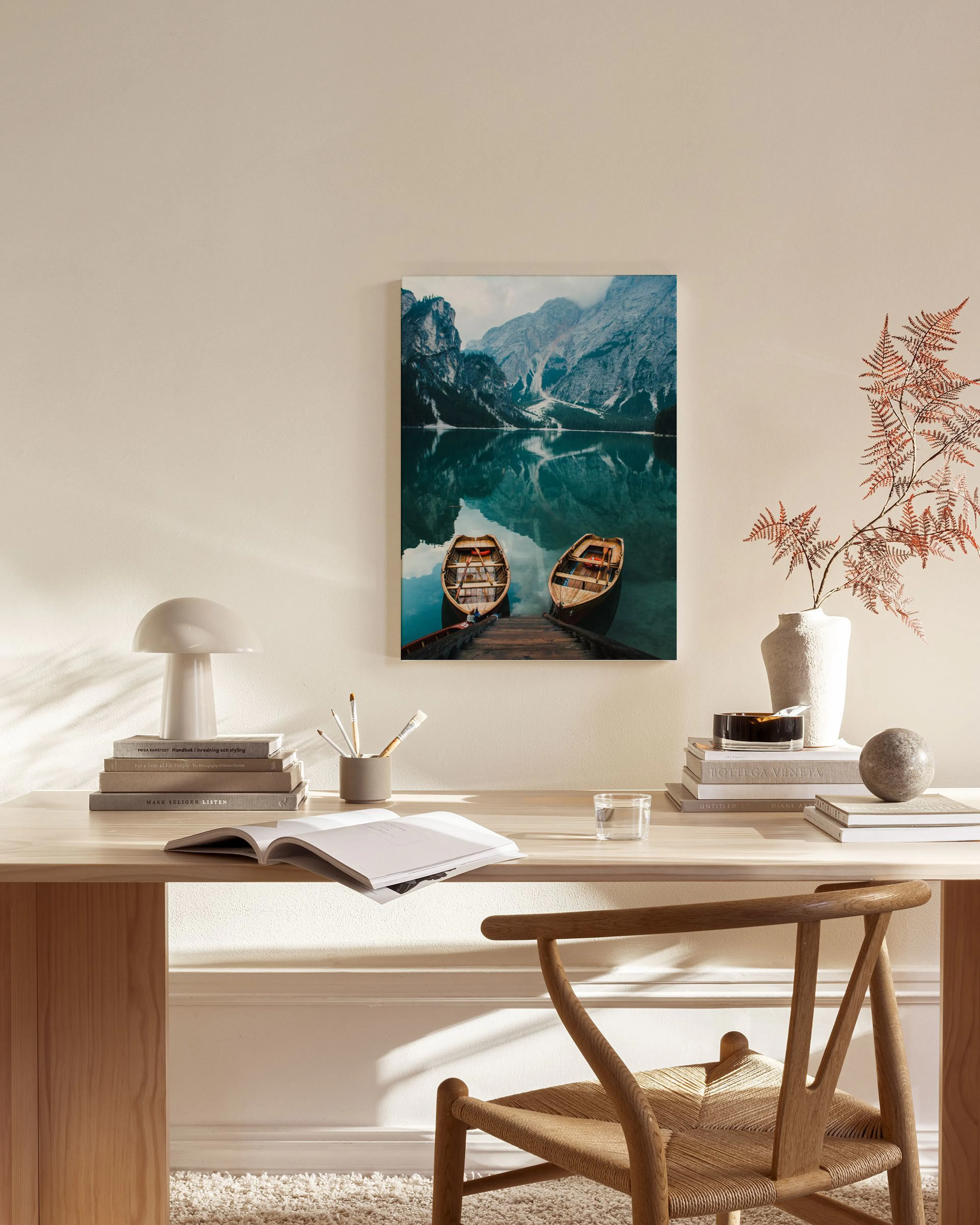 Toile dun lac de montagne bleu-vert avec deux bateaux à quai, reflétant les montagnes, accrochée dans un salon moderne.