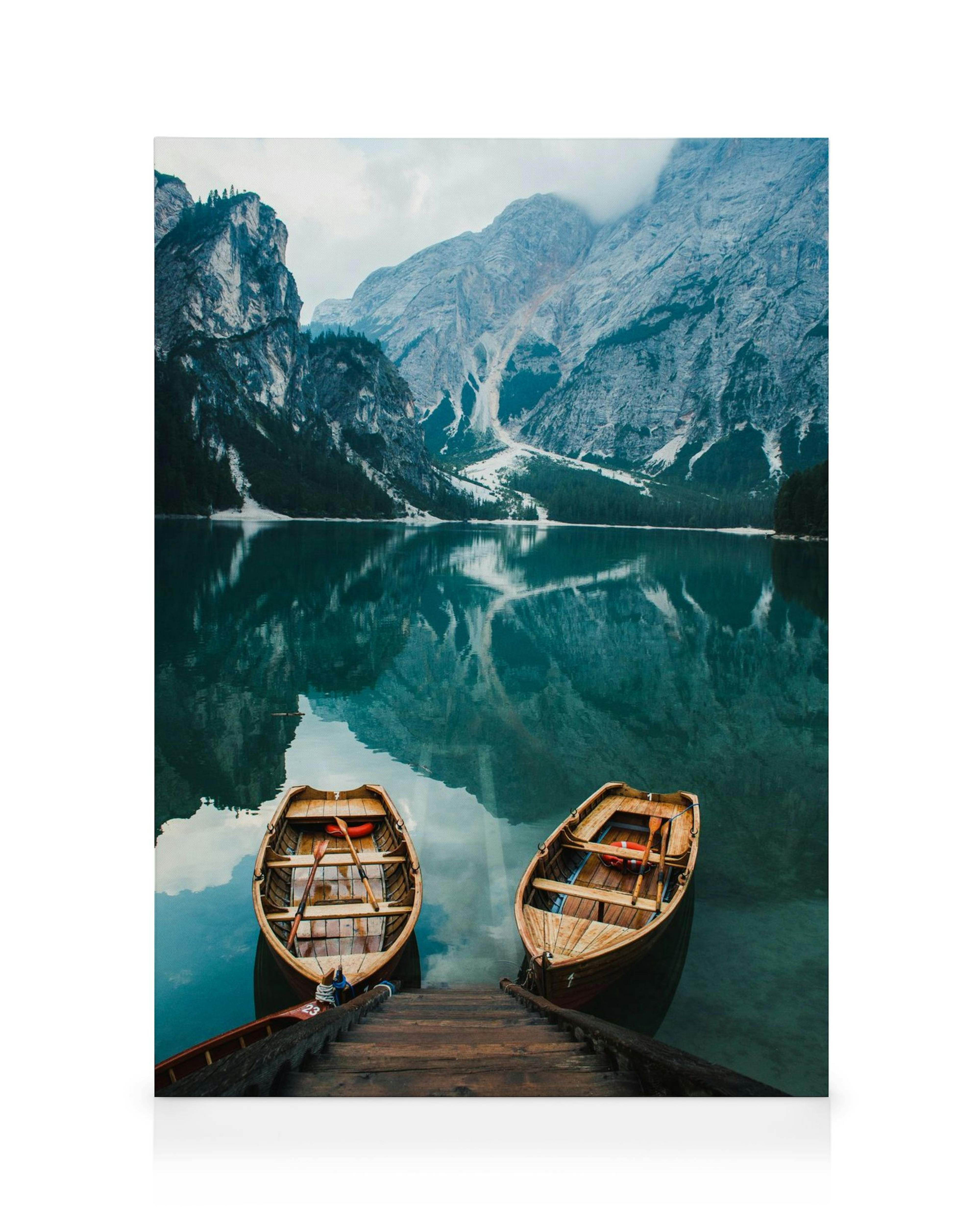 Two wooden boats in a still lake with reflections of foggy mountains on a nature canvas print.