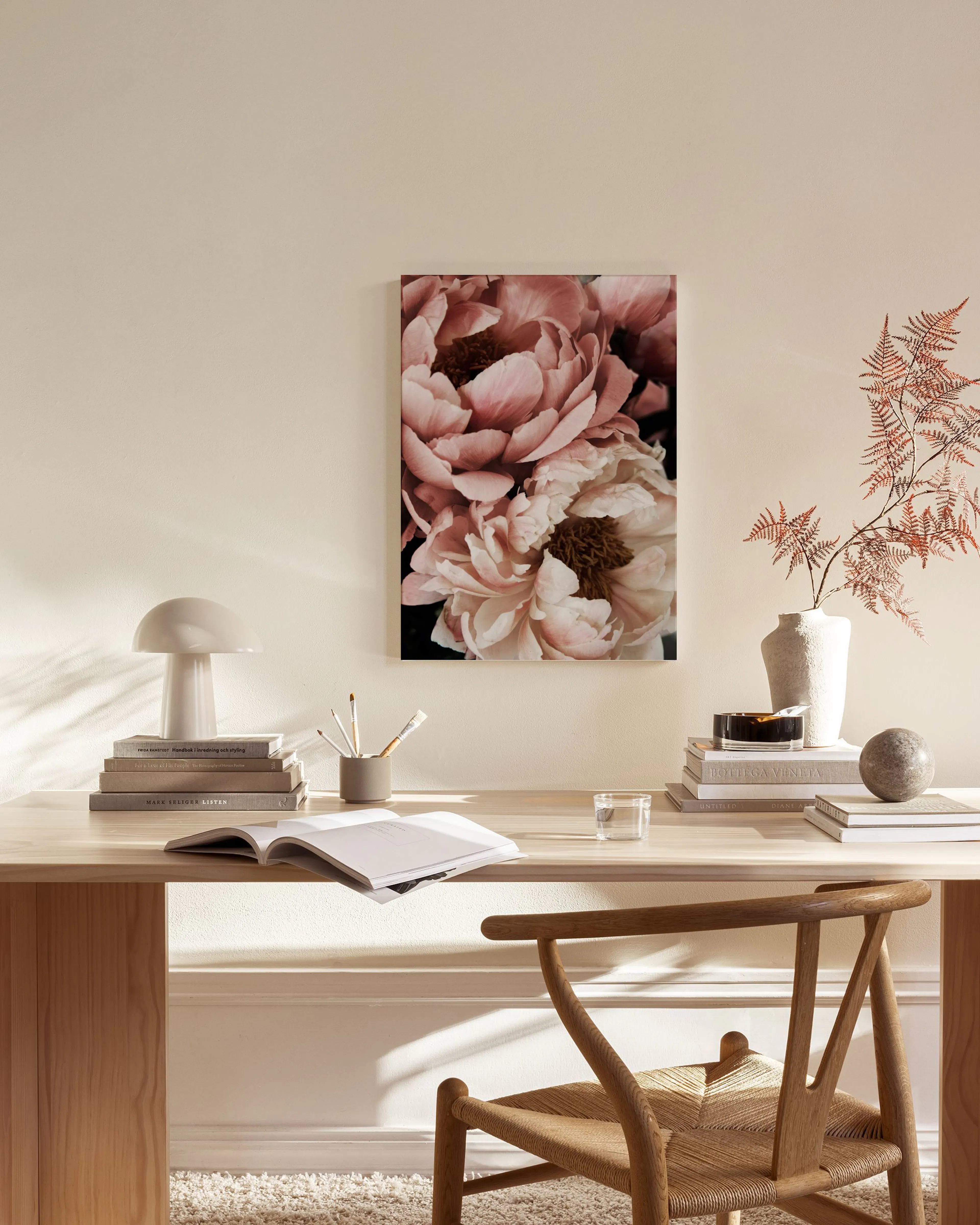 Canvastavla med närbild av två rosa pioner, hängande i ett ljust vardagsrum över en bänk och soffbord.
