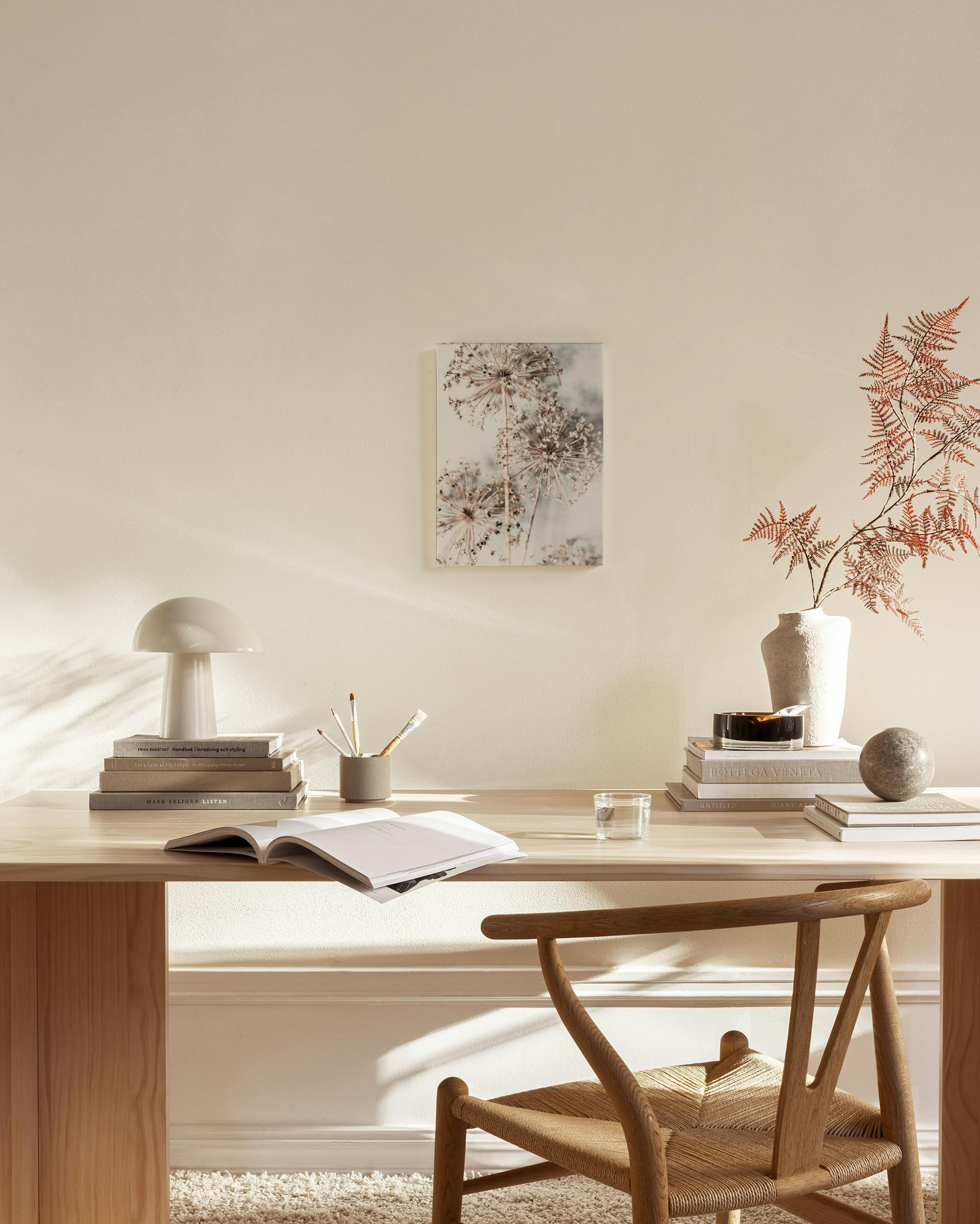 Botanical canvas print of dried seed heads on a light background, hanging in a light-filled living room.