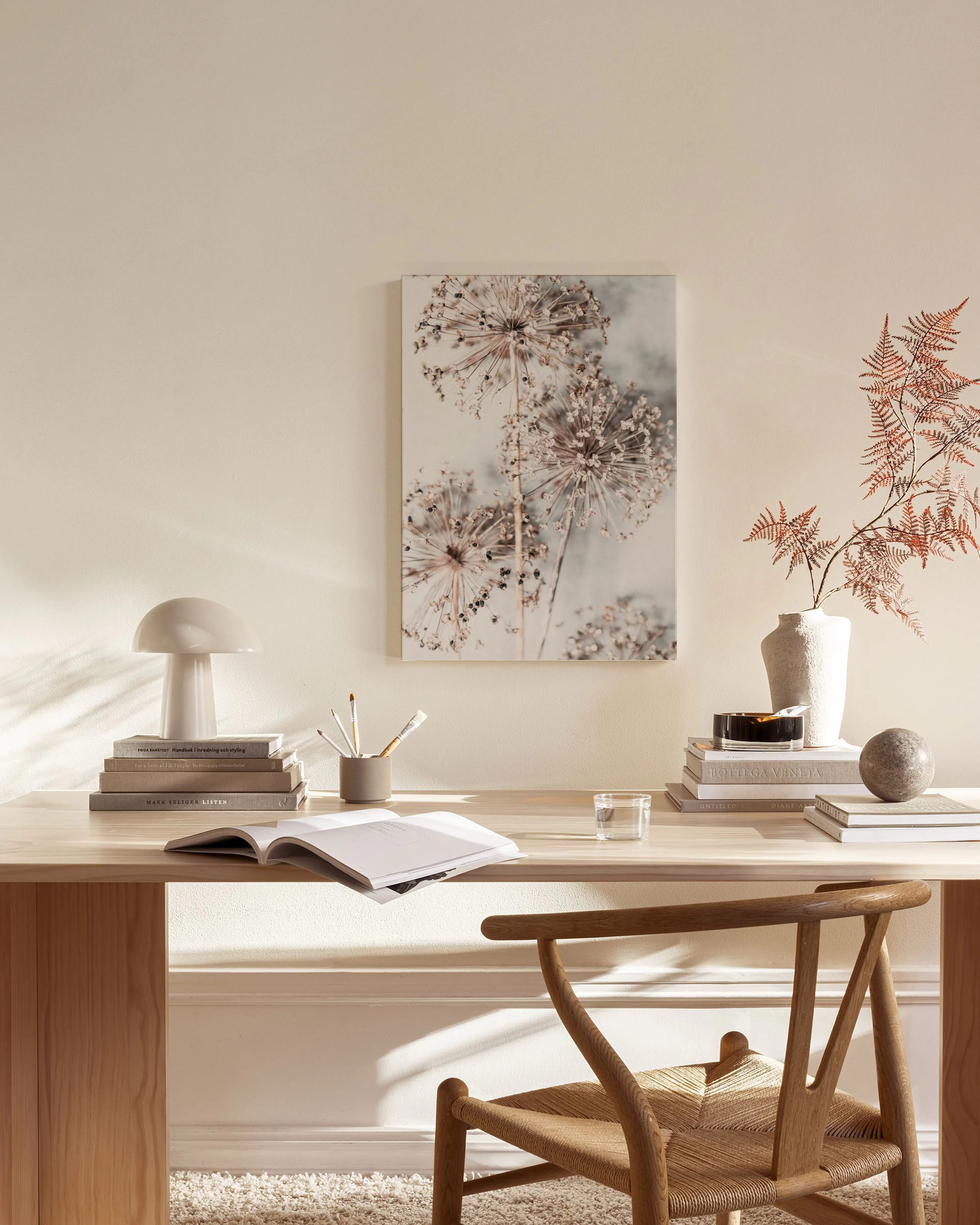 Een canvas met een close-up van gedroogde, pluizige bloemen in natuurlijke tinten, hangend in een lichte woonkamer.