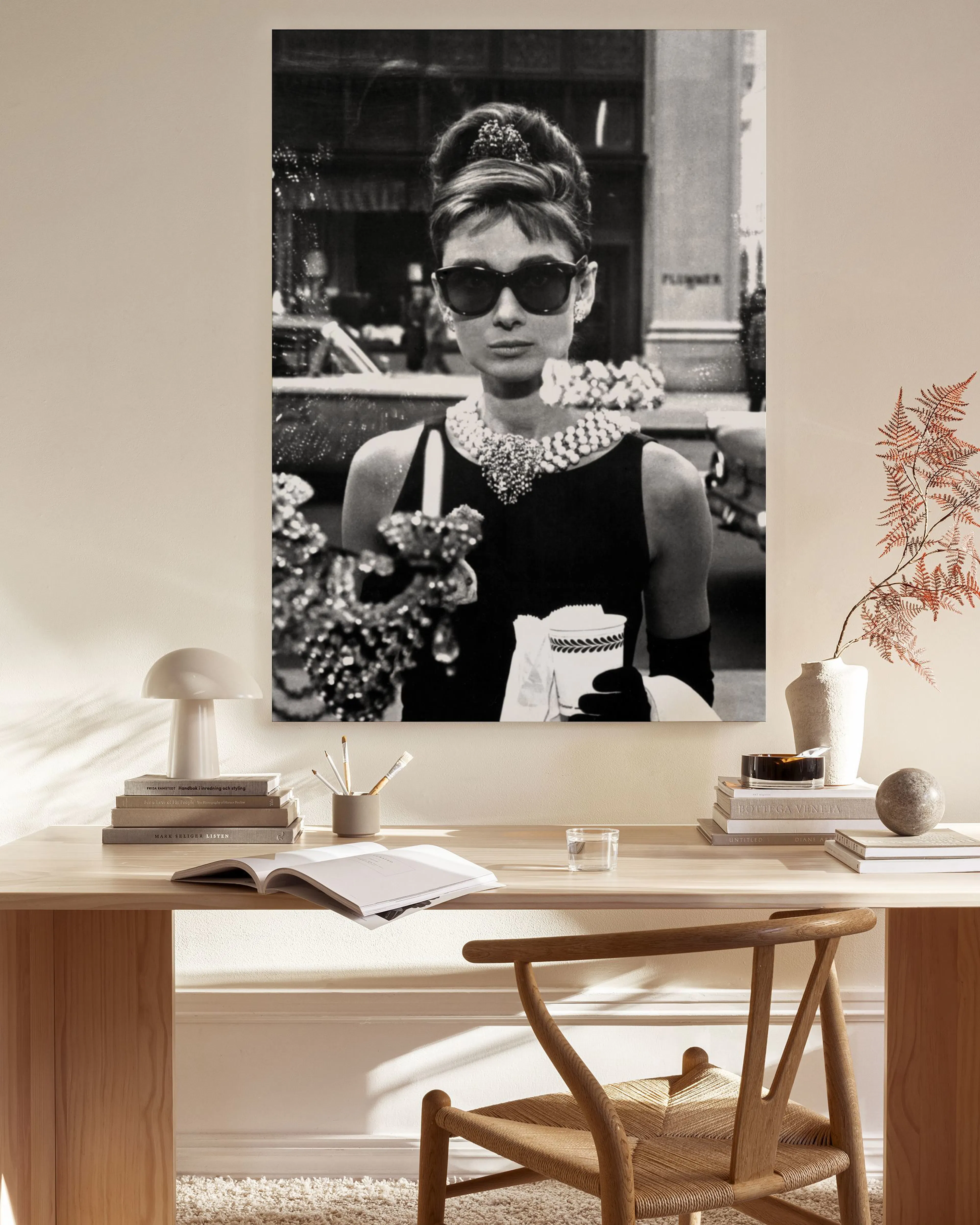 Ασπρόμαυρος καμβάς με την Audrey Hepburn να φοράει γυαλιά ηλίου και κολιέ, κρεμασμένος σε μοντέρνο σαλόνι.