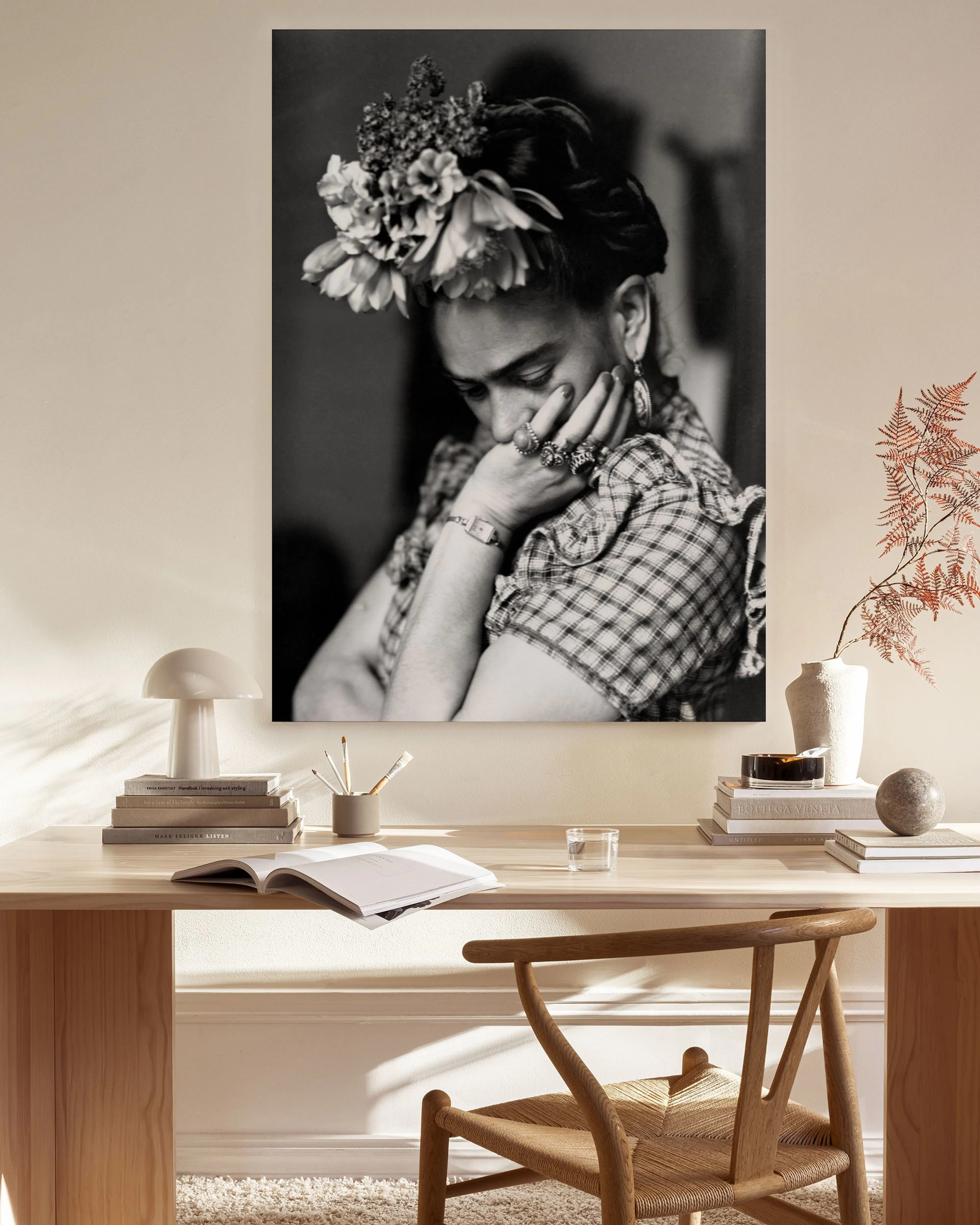 Zwart-wit canvas van Frida Kahlo met bloemen in haar haar, hangend in een neutrale woonkamer met houten meubels.