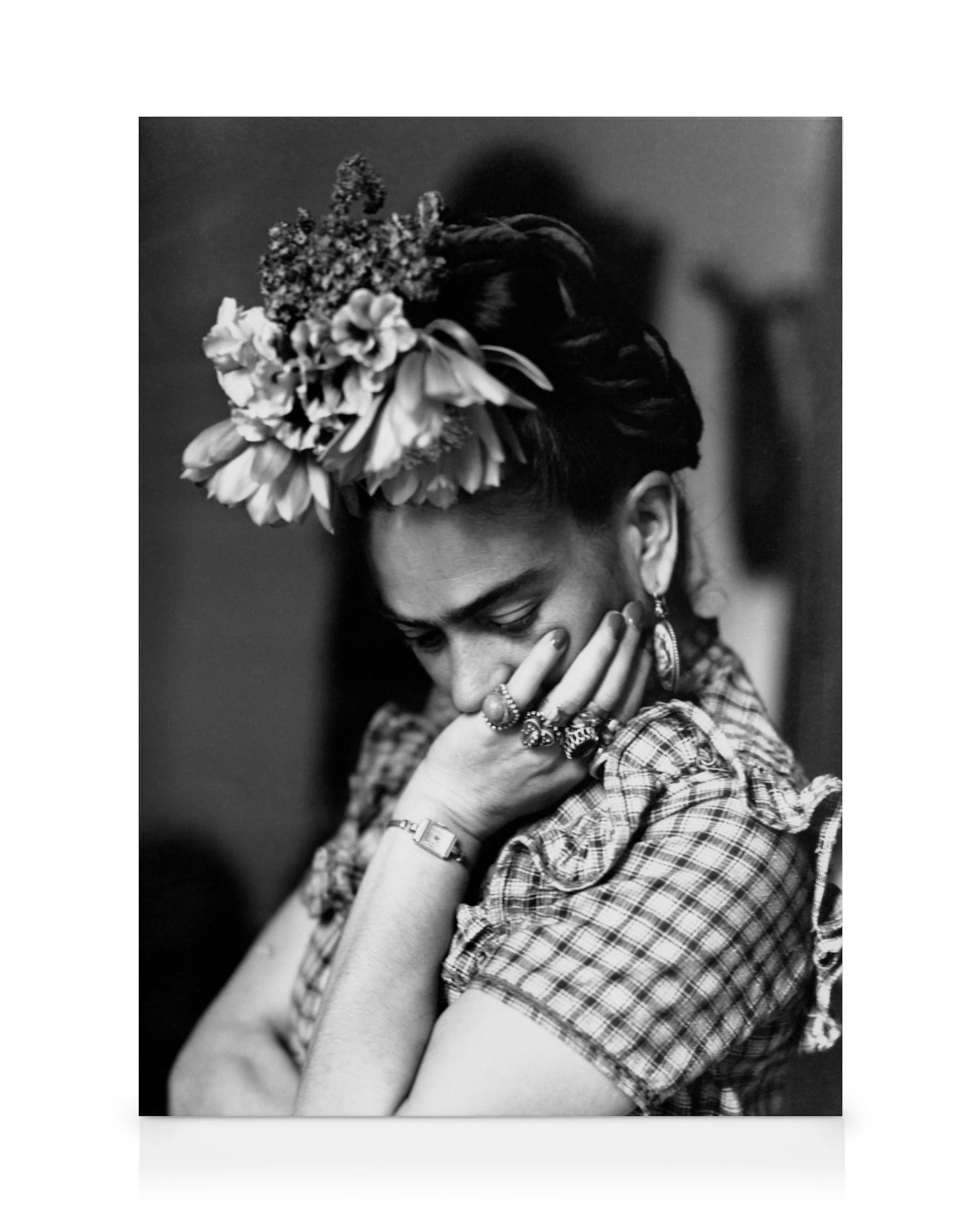 Zwart-wit canvas van kunstenares Frida Kahlo met bloemen in haar haar en ringen aan haar hand, leunend op haar arm.