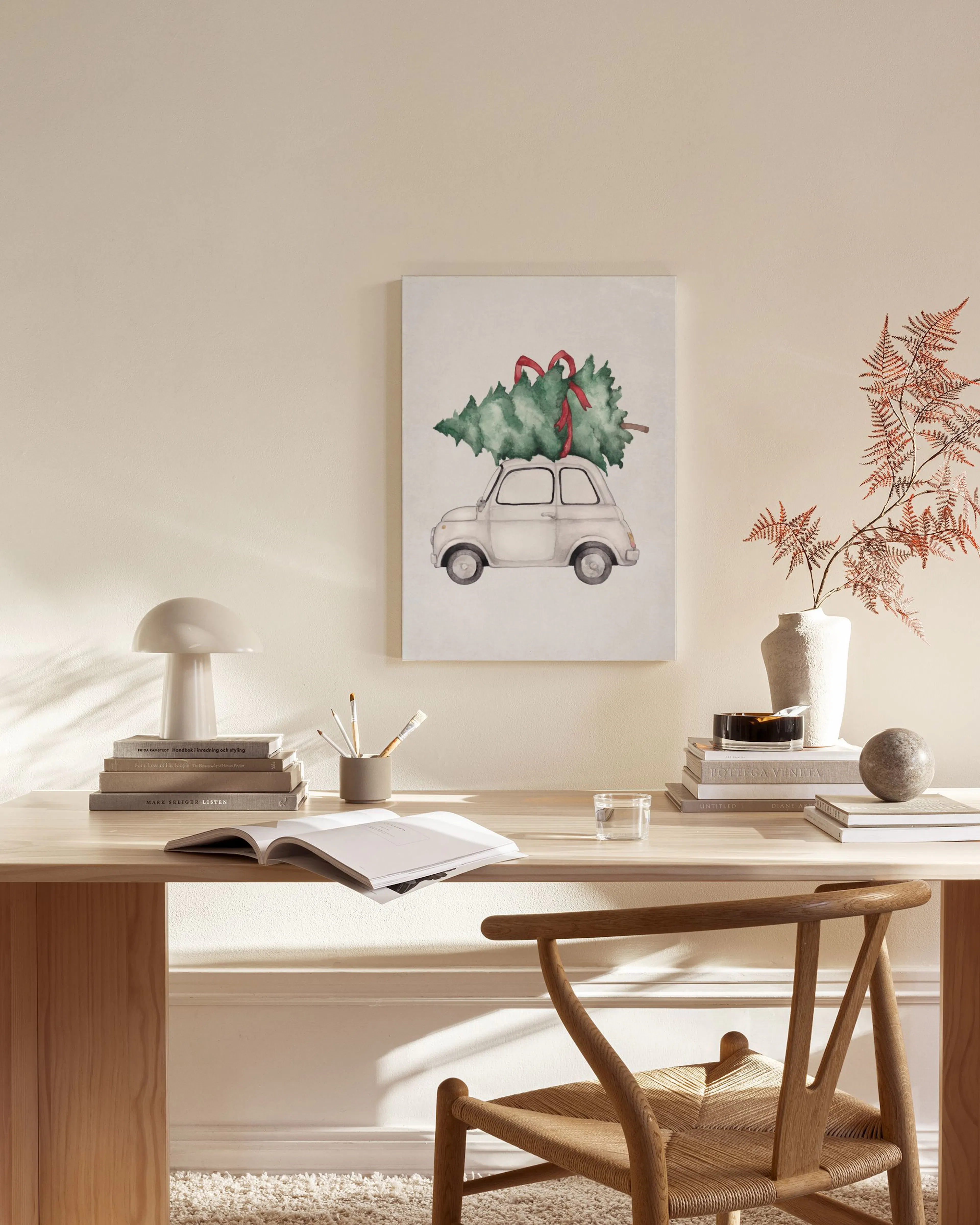 A watercolor print of a white vintage car with a Christmas tree on its roof, hanging in a modern living room.