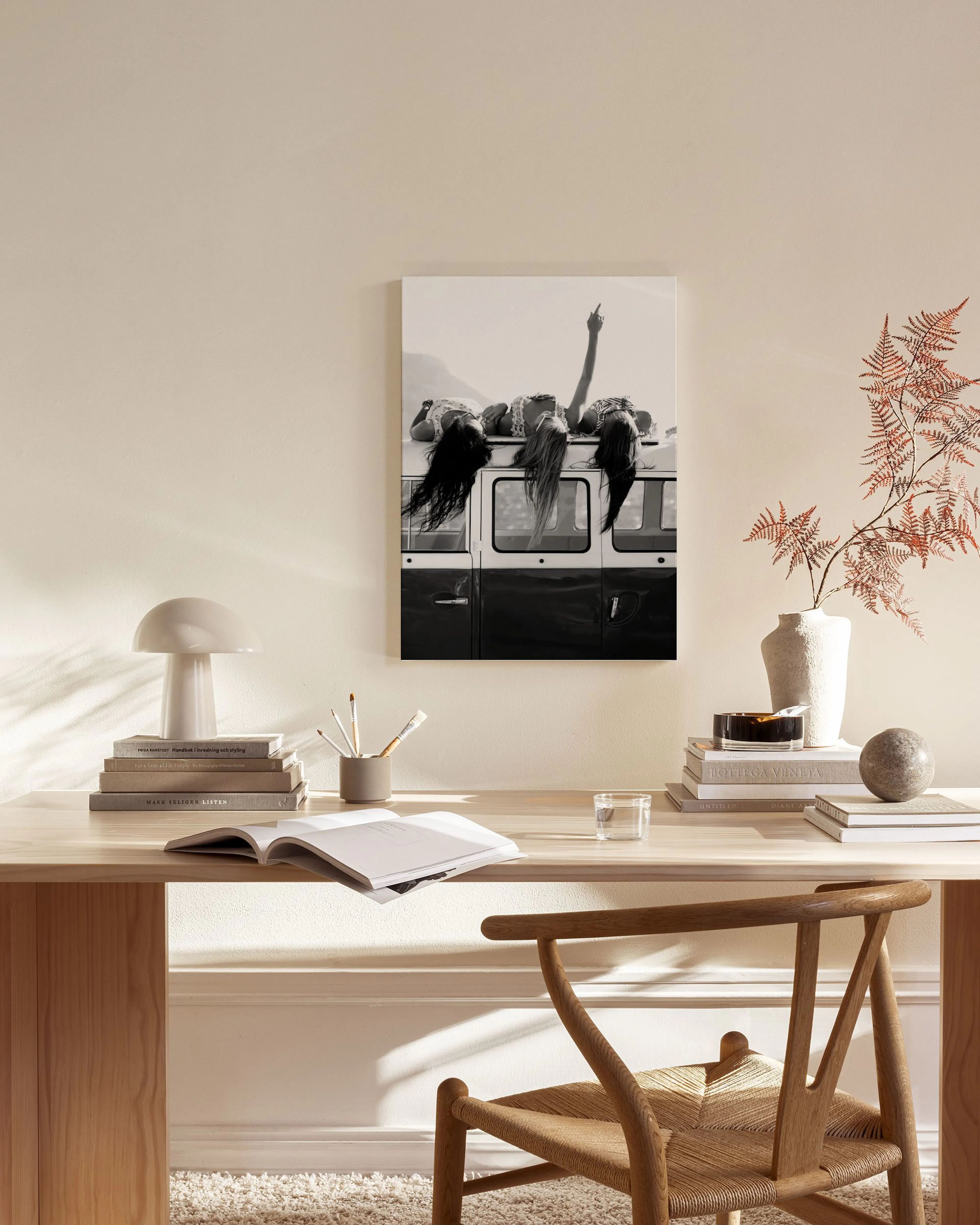 Black and white canvas print of four people lying on the roof of a van, displayed in a modern living room.