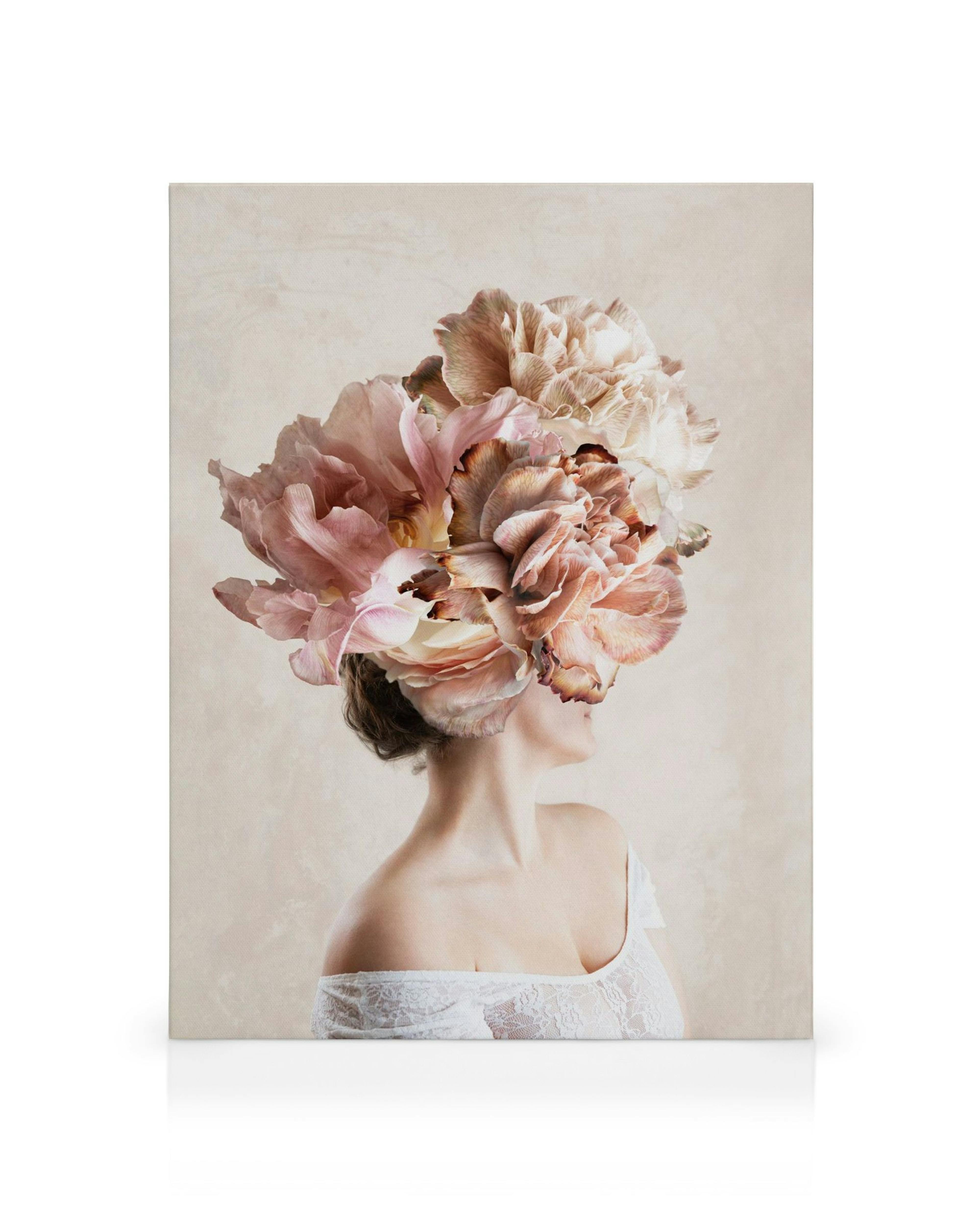 Nainen, jonka pää on valtavista, vaaleanpunaisista ja beigenvärisistä kukista muodostuva kukkakimppu, valkoisessa pitsitopissa