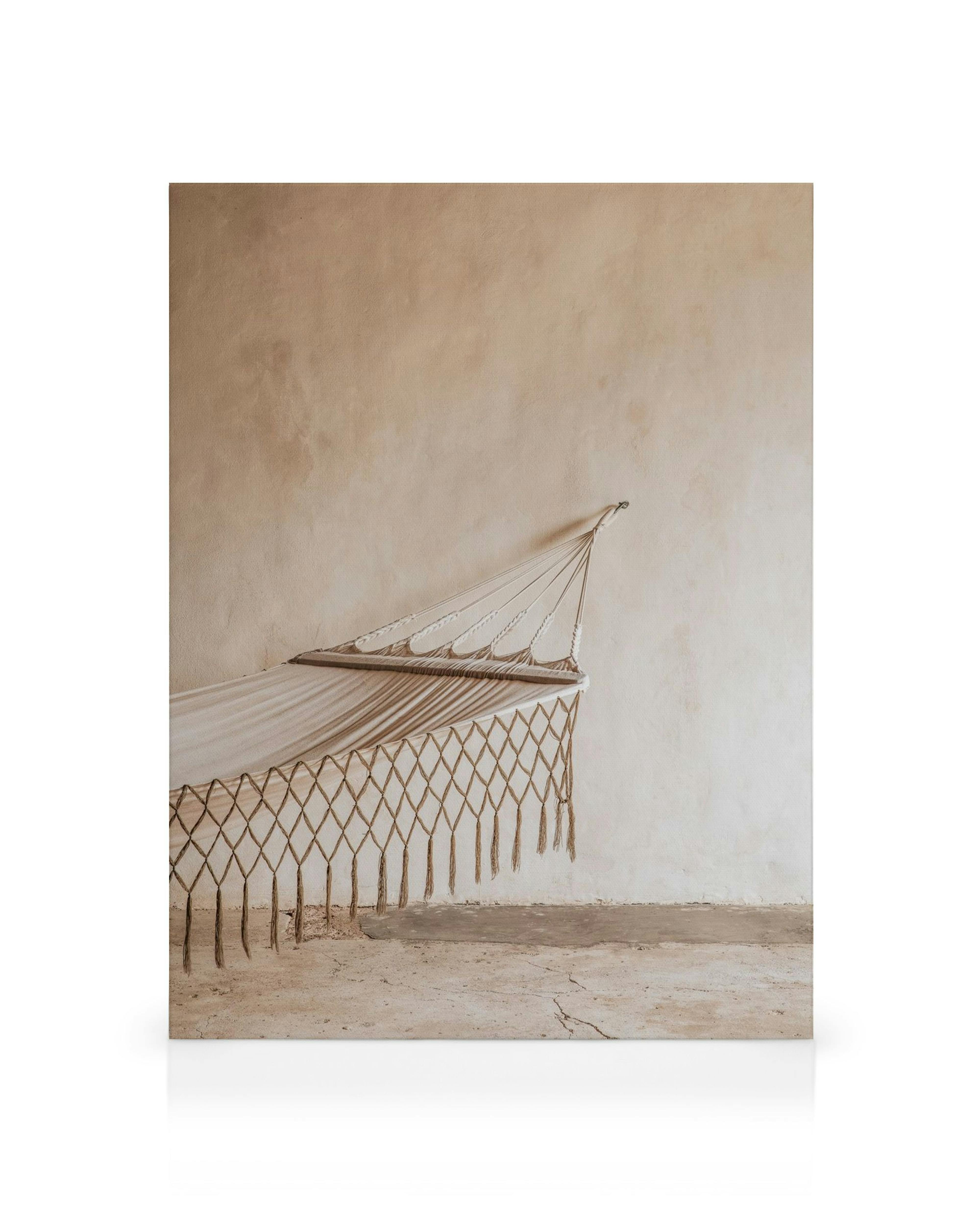 Hängematte aus Segeltuch und Seil vor einer beigen Wand, die Ruhe und Entspannung symbolisiert
