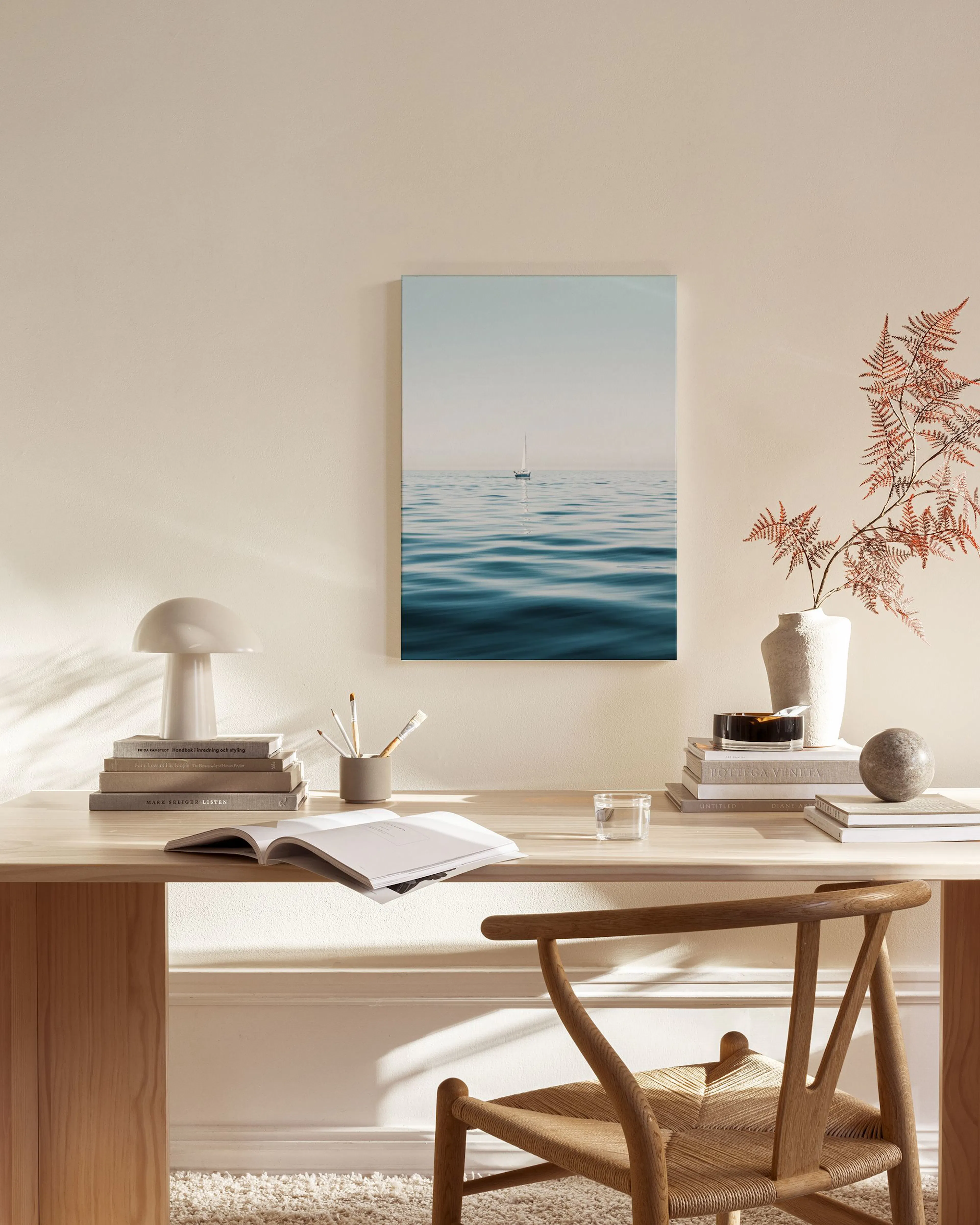 Canvas met zeilboot op kalm blauw water onder een lichte hemel, hangend in een moderne woonkamer.