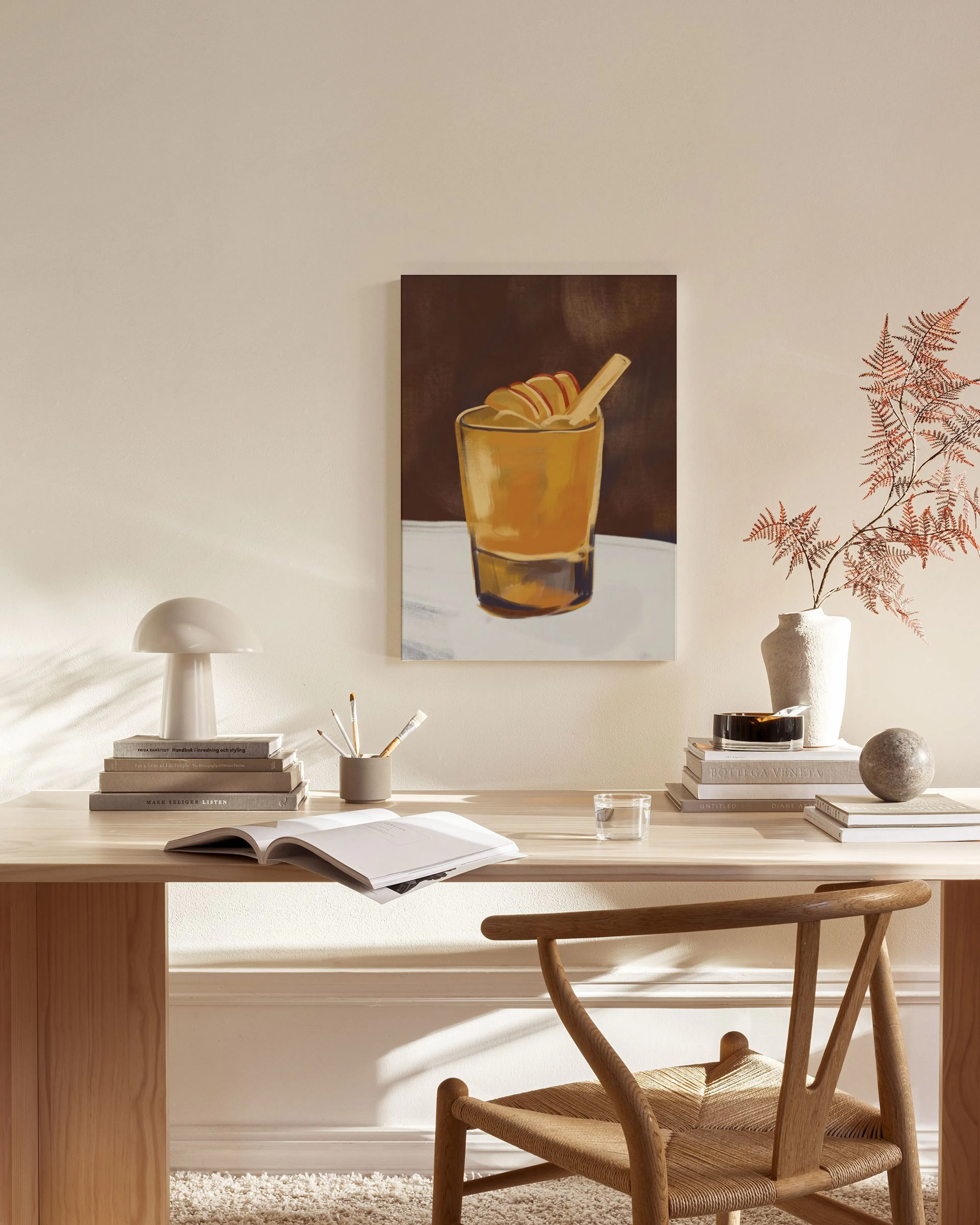 Leinwandbild mit einem Cocktail in einem Glas, dekoriert mit Zimtstange und Apfelspalten, hängt in einem modernen Wohnzimmer.