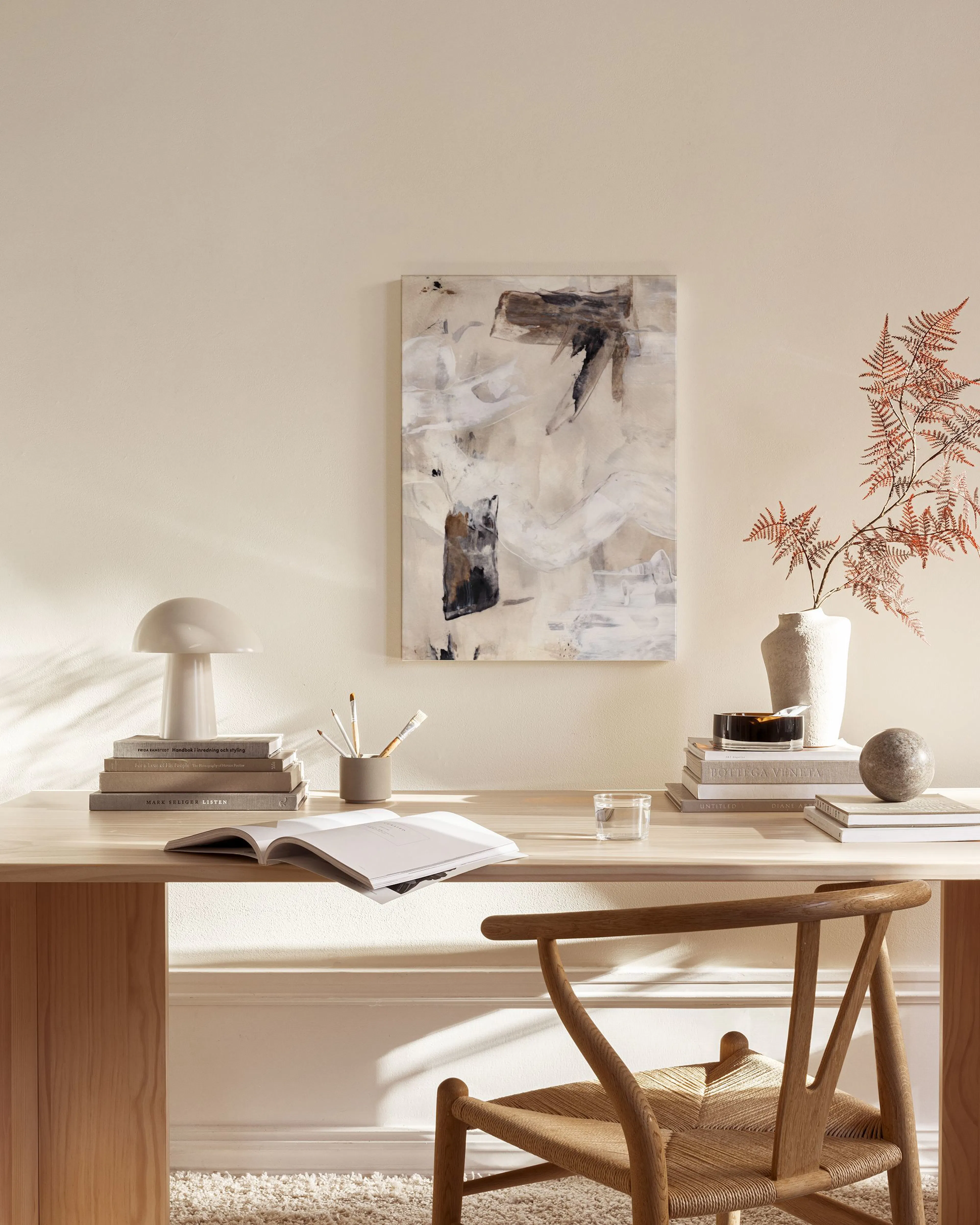 Lienzo abstracto con manchas marrones, grises y blancas, colgado en una sala de estar moderna sobre un mueble bajo.
