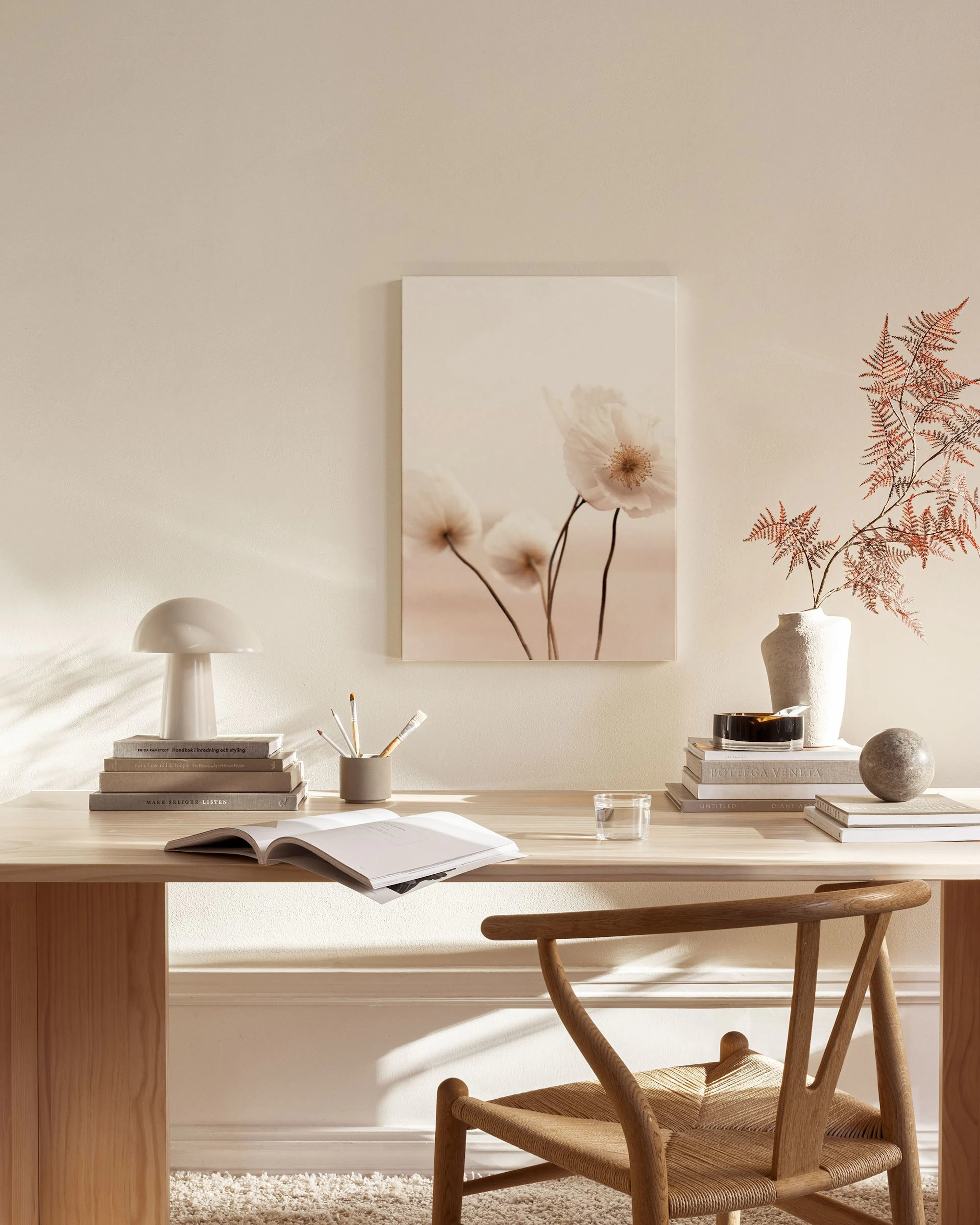 Toile murale de trois coquelicots blancs aux tiges fines, sur fond rose pâle, affichée dans un salon moderne.