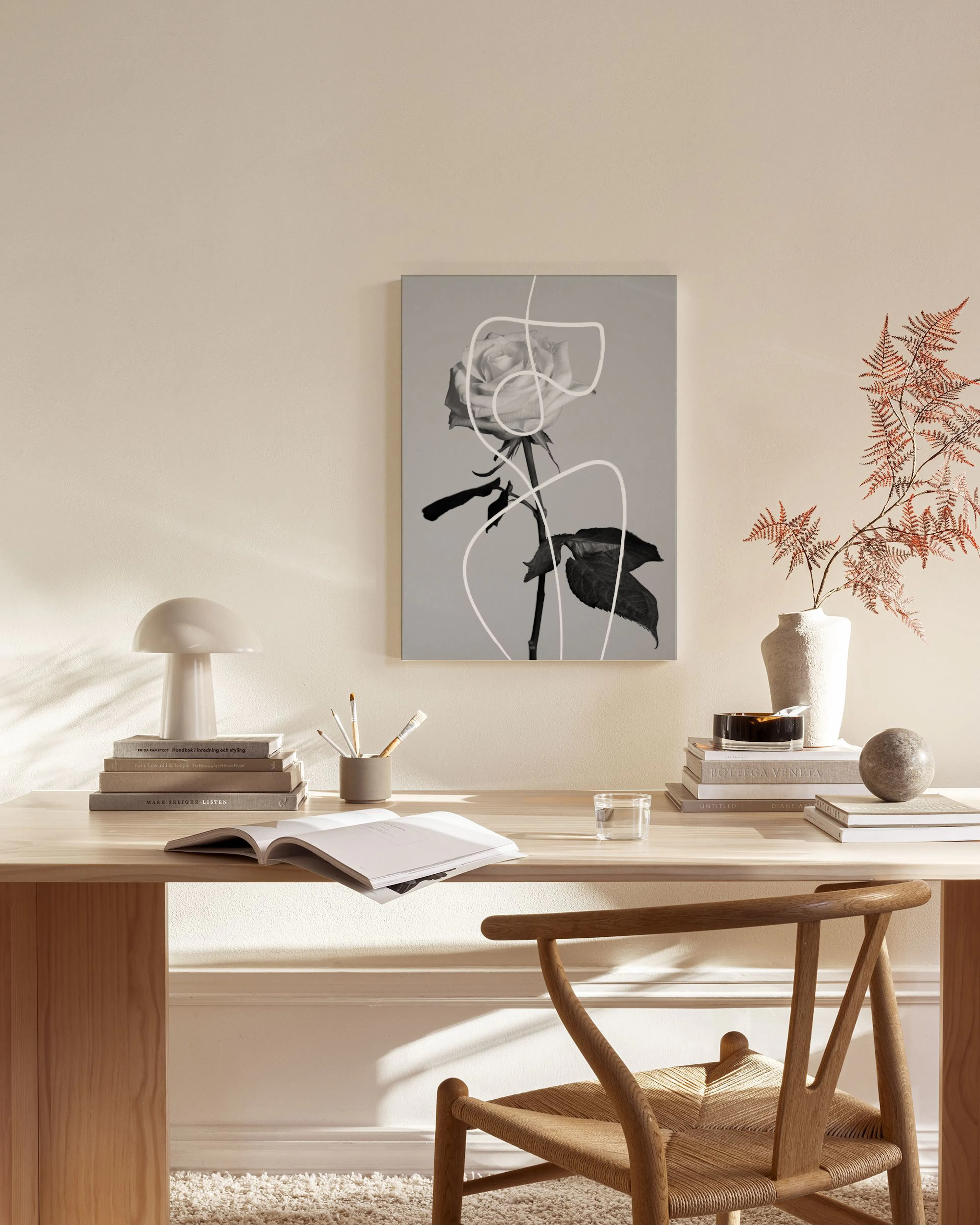 A canvas print of a black and white rose with white abstract line art, hanging above a wooden console in a modern living room.