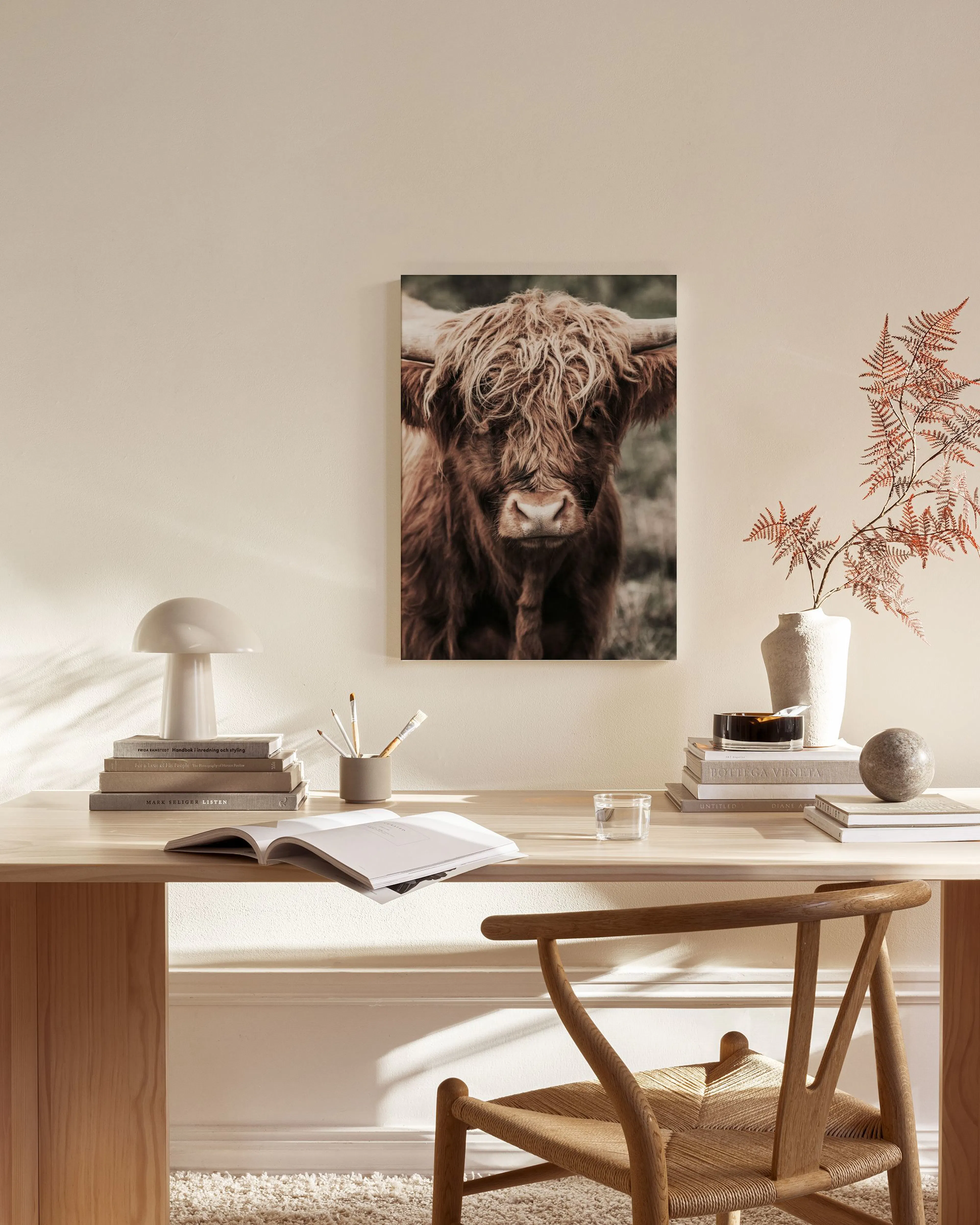 Leinwandbild einer braunen Hochlandrind-Kuh mit zotteligem Fell, hängend über einem Sideboard in einem modernen Wohnzimmer.