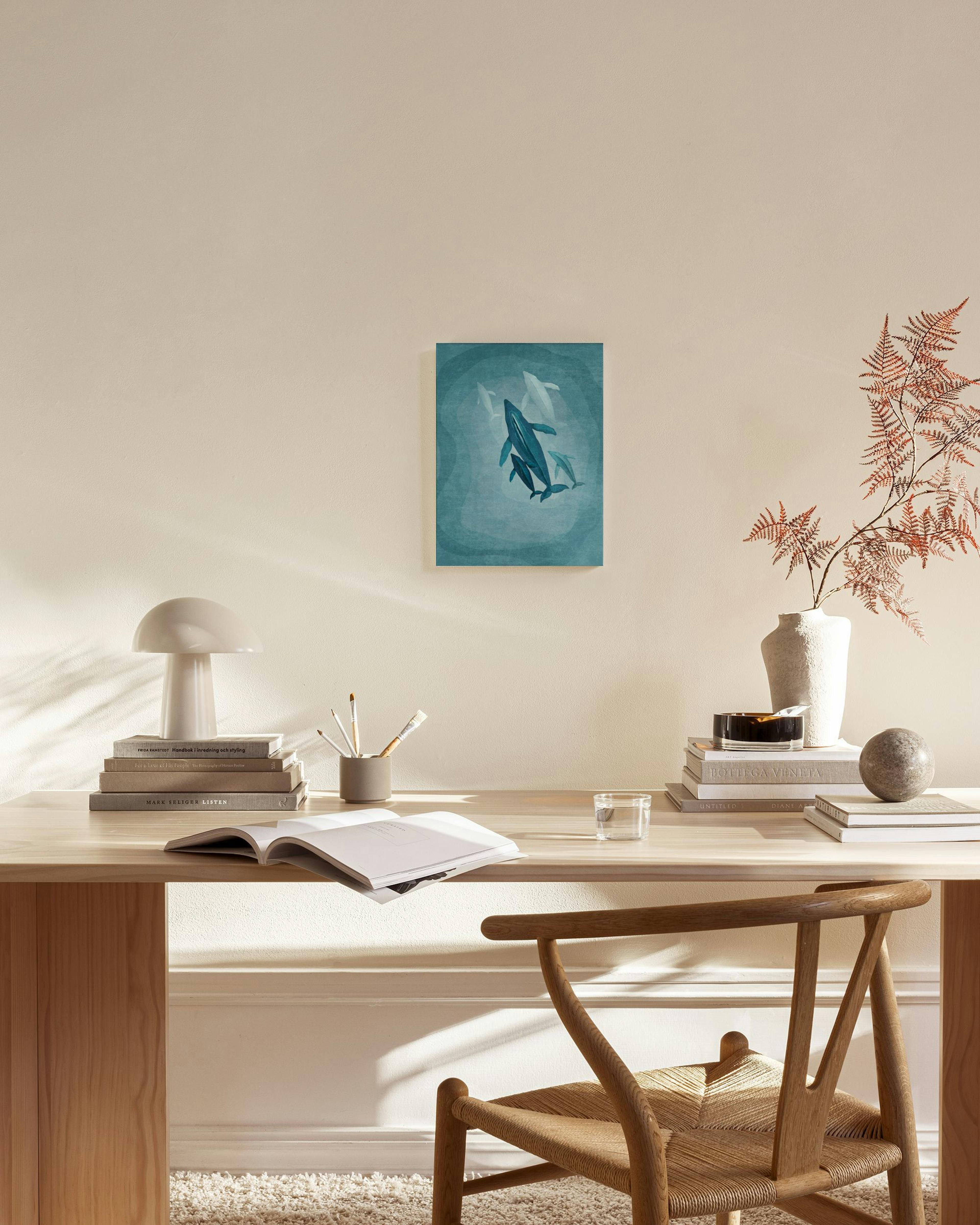 Lærred med en hvalfamilie i mørkeblå nuancer, hængende over en træbænk i en moderne stue.