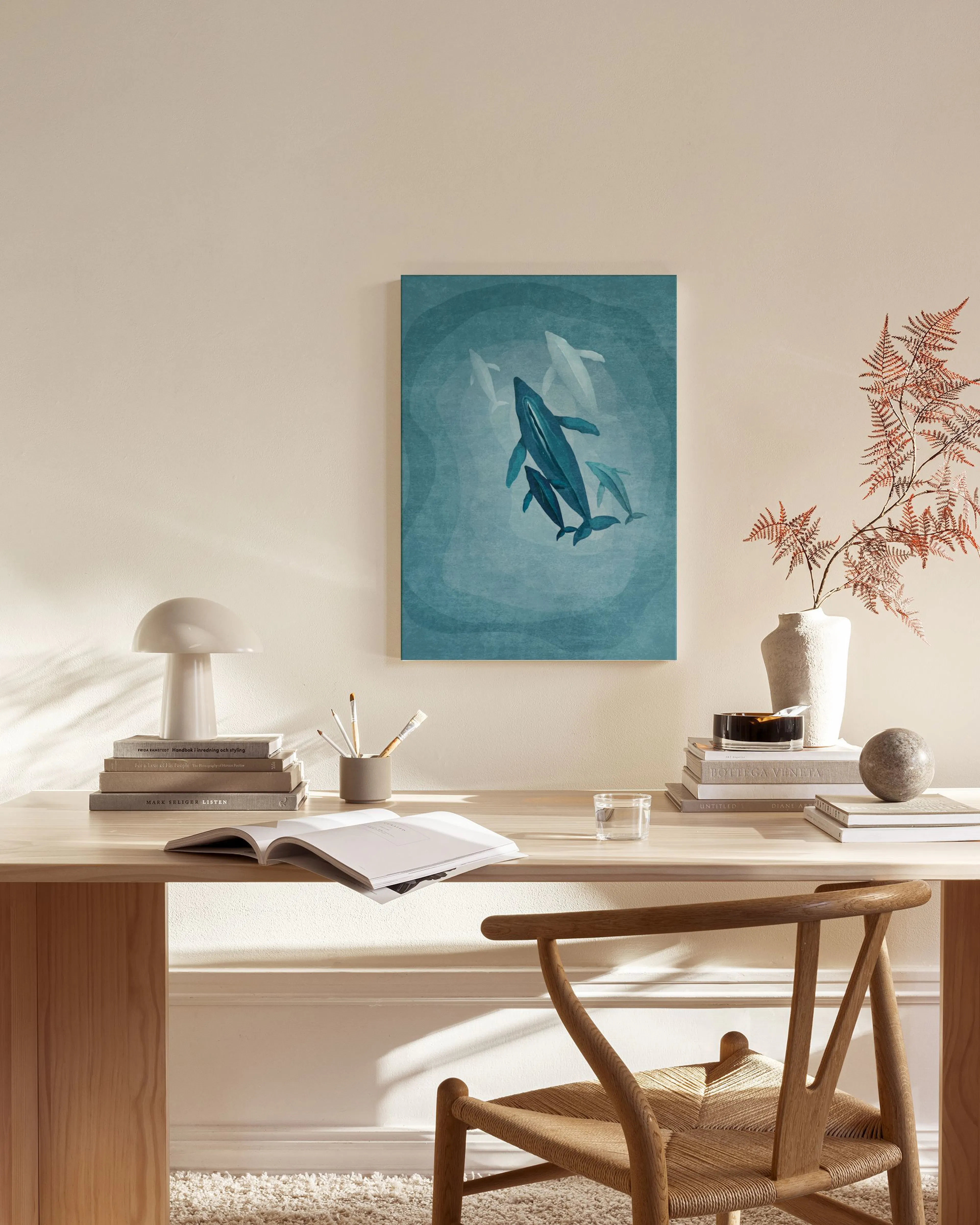 A canvas print of blue whales swimming in deep blue water, hanging above a wooden sideboard in a contemporary living room.