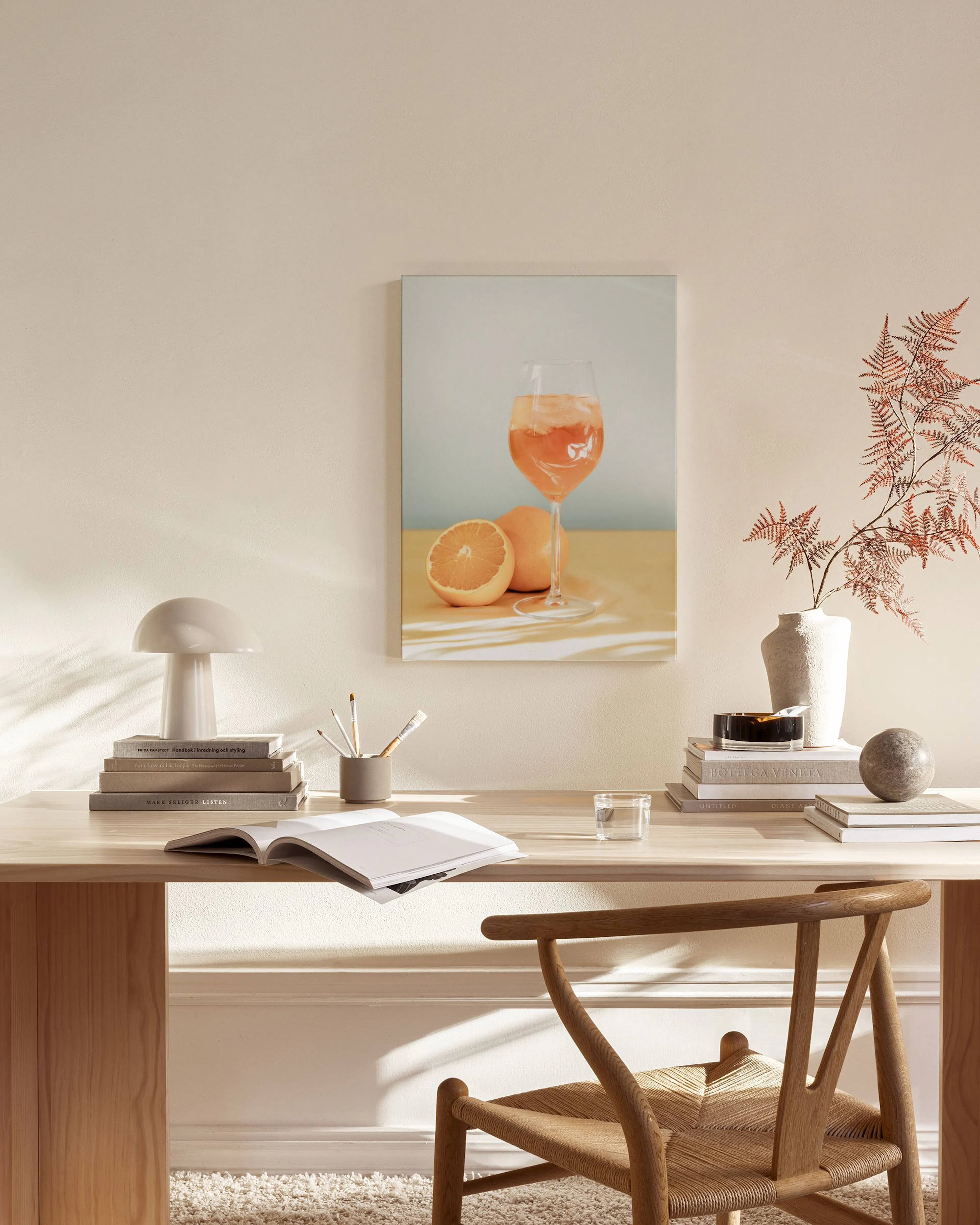 Lærred med glas aperol og appelsiner i en stue over et træmøbel og et glas sofabord.