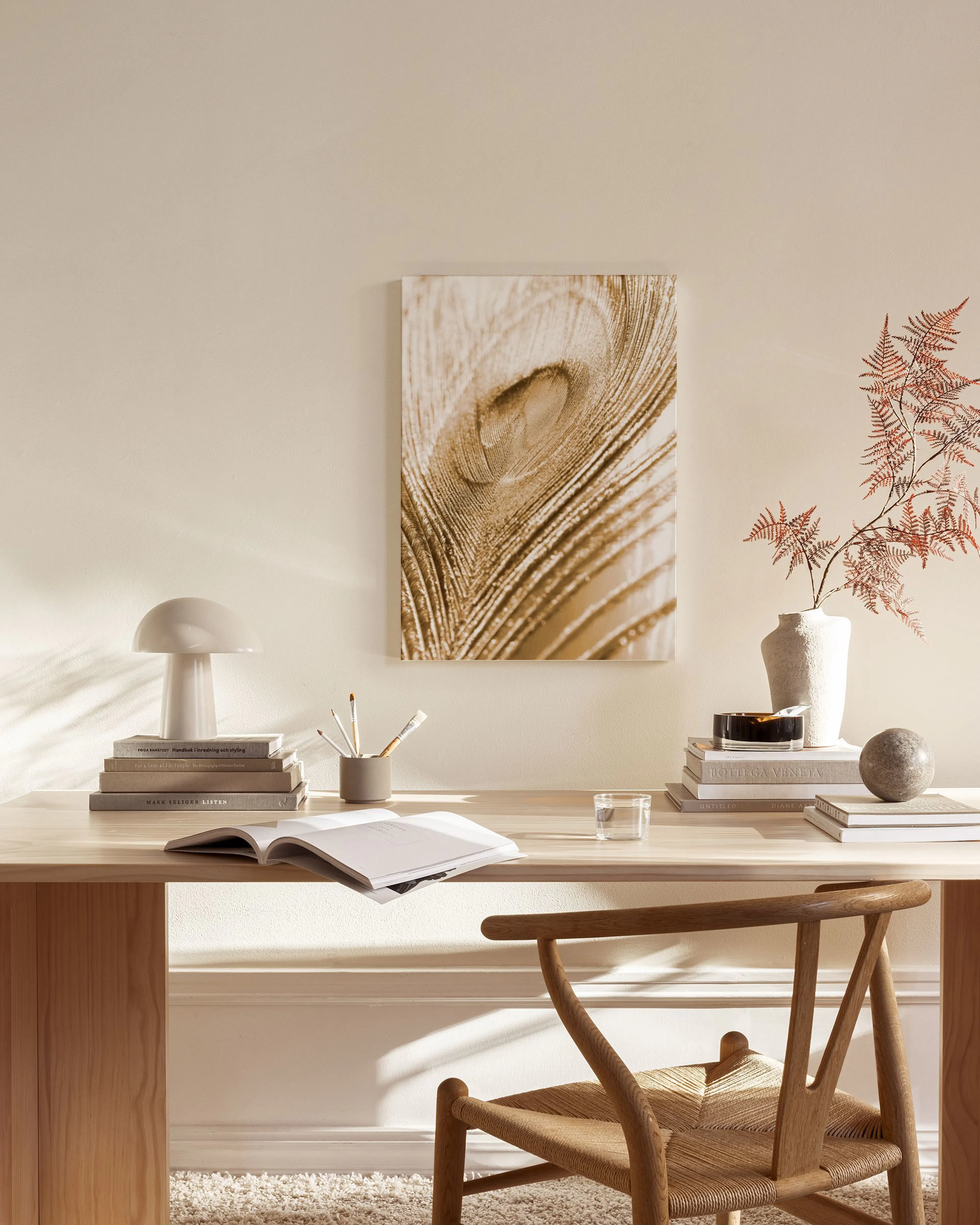 Toile murale marron clair représentant une plume de paon, accrochée dans un salon moderne aux tons neutres.