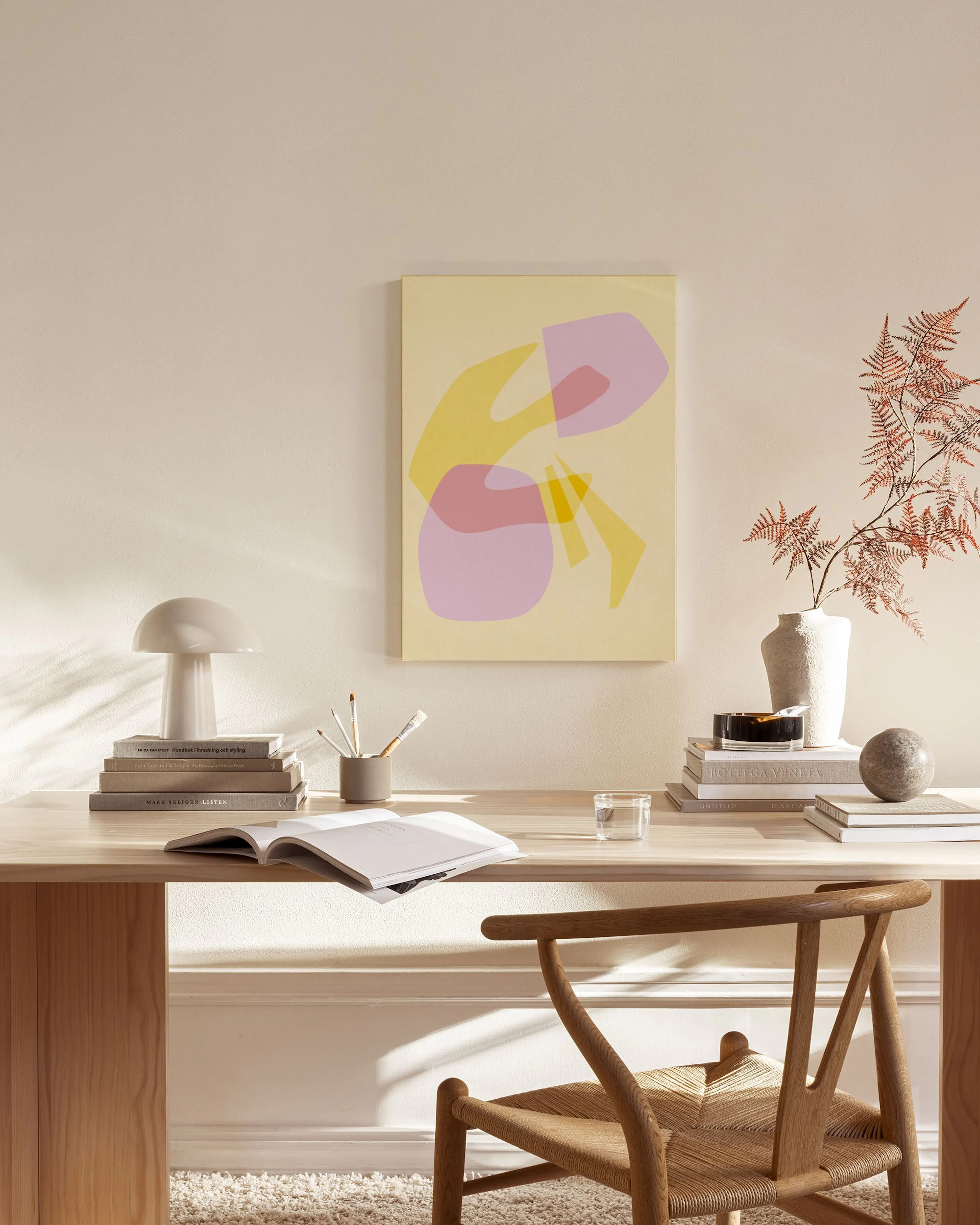 Leinwandbild mit überlappenden organischen Formen in Gelb, Rosa und Lila, an einer beigen Wand in einem Wohnzimmer.