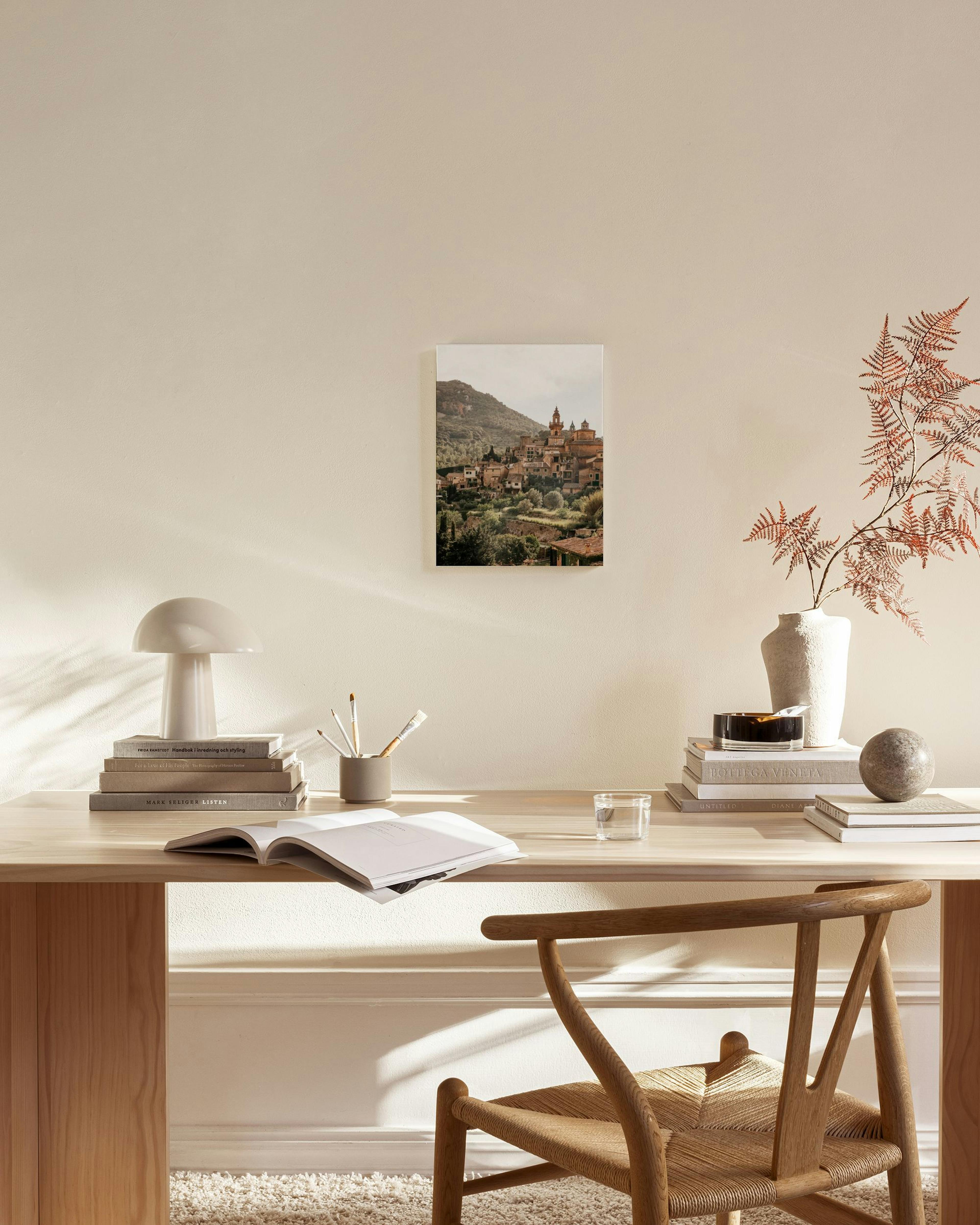 Toile murale dun village méditerranéen sur une colline verdoyante, affichée dans un salon moderne aux tons neutres.