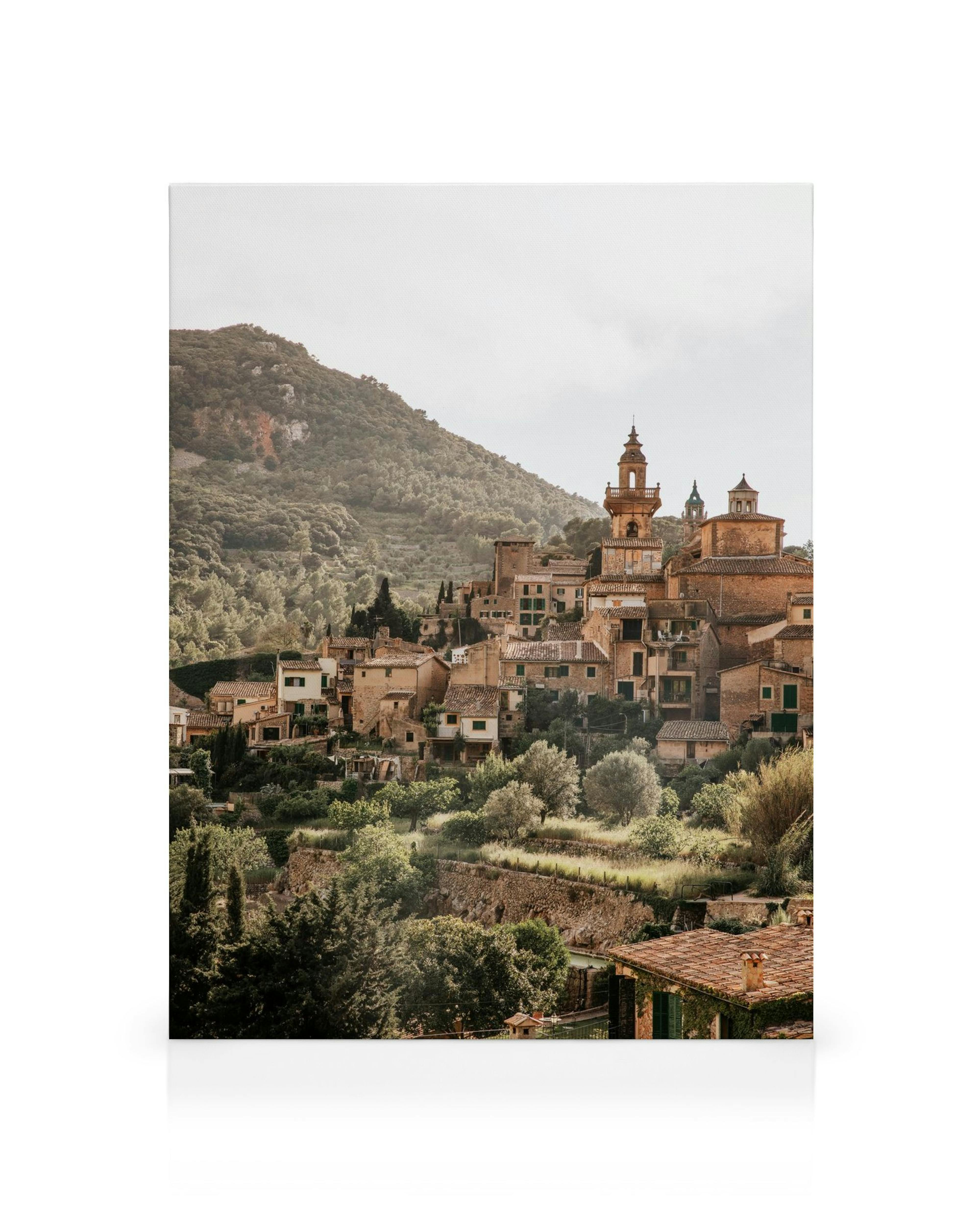 Toile dun village italien sur une colline, avec maisons, clochers et arbres verts sous un ciel nuageux au style méditerranéen