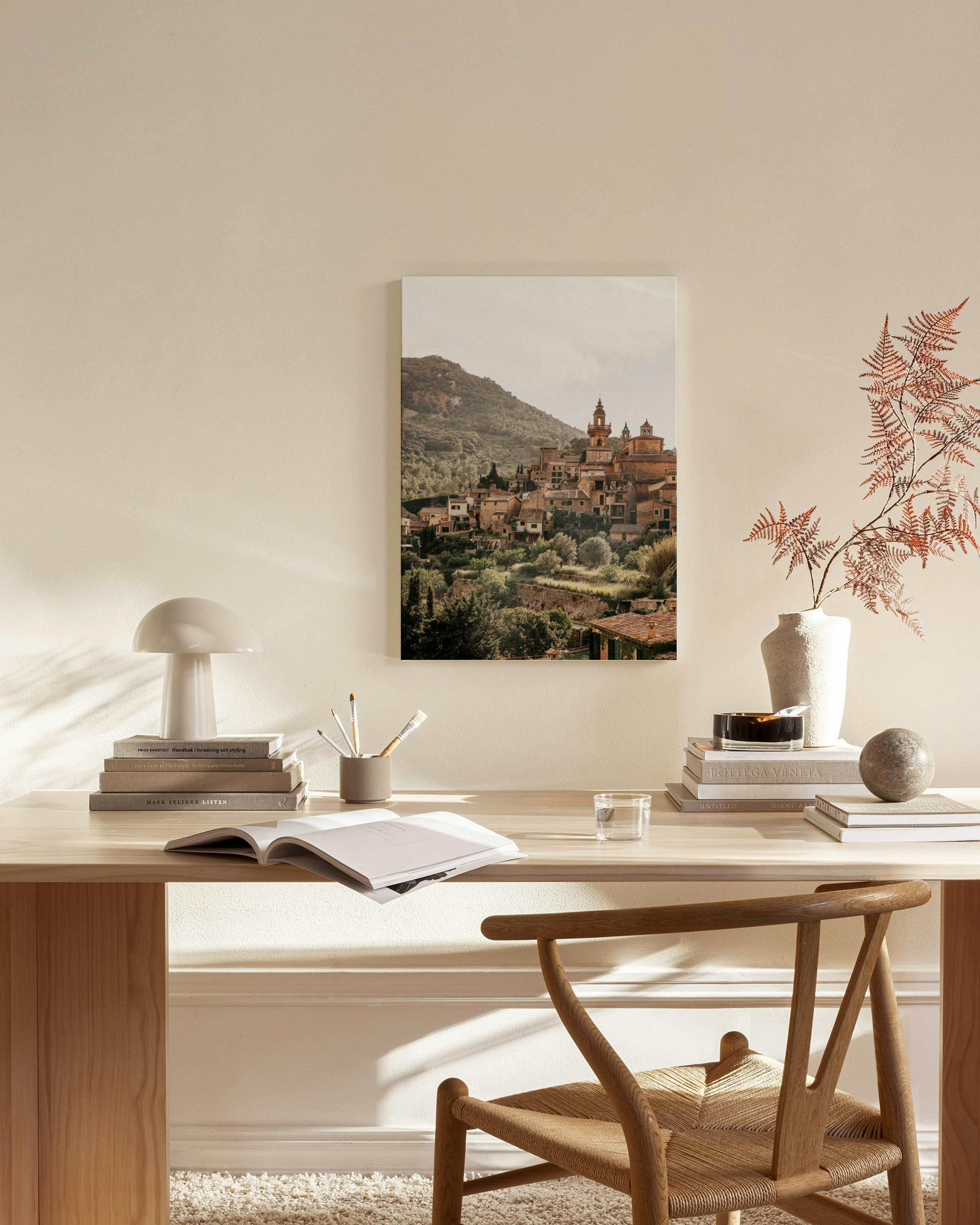 Canvas van een dorp op een heuvel in een zonnig landschap, hangend in een neutrale woonkamer.