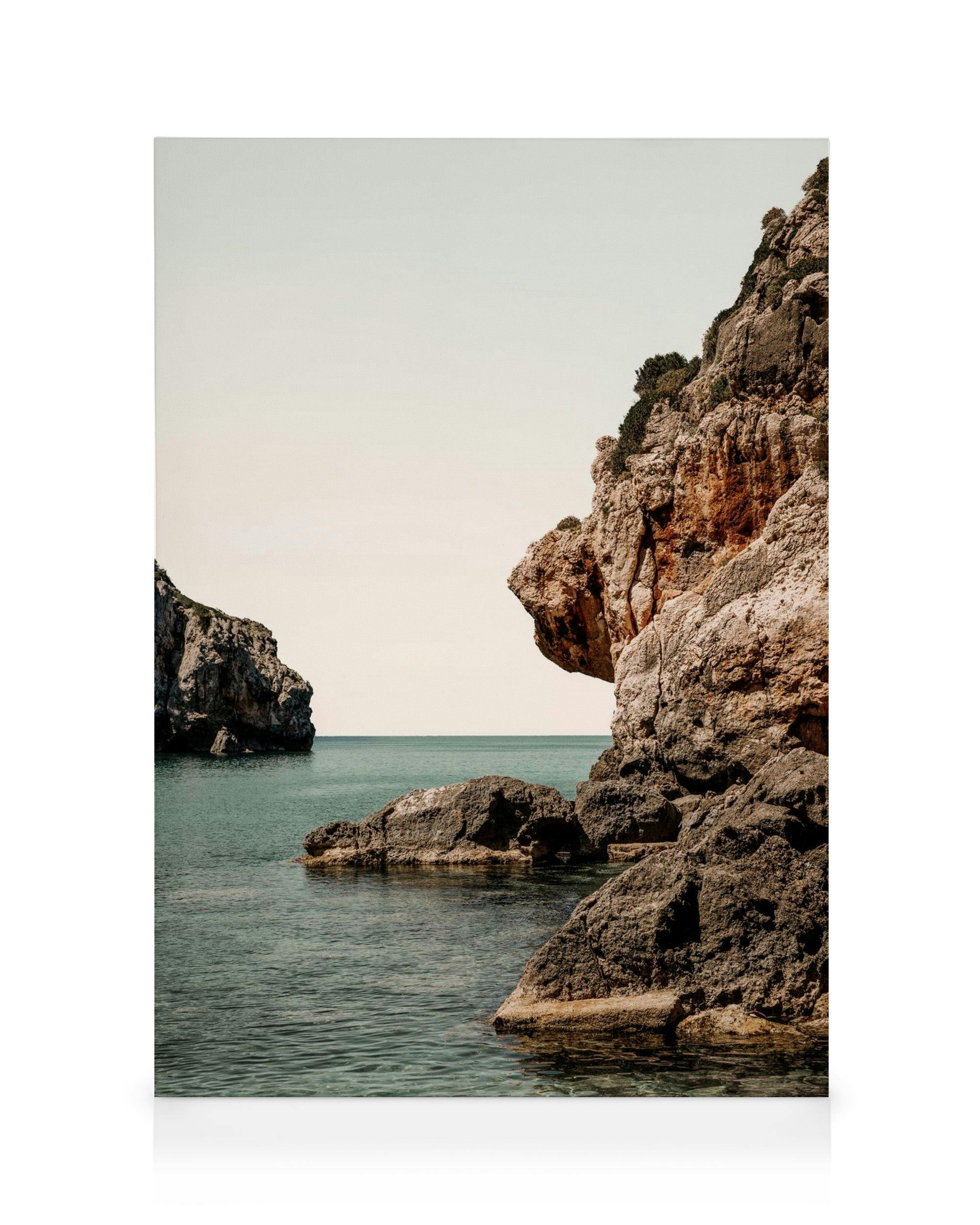 Leinwanddruck mit Felsformationen am Meer, klares türkises Wasser, heller Himmel, Küstenlandschaft.