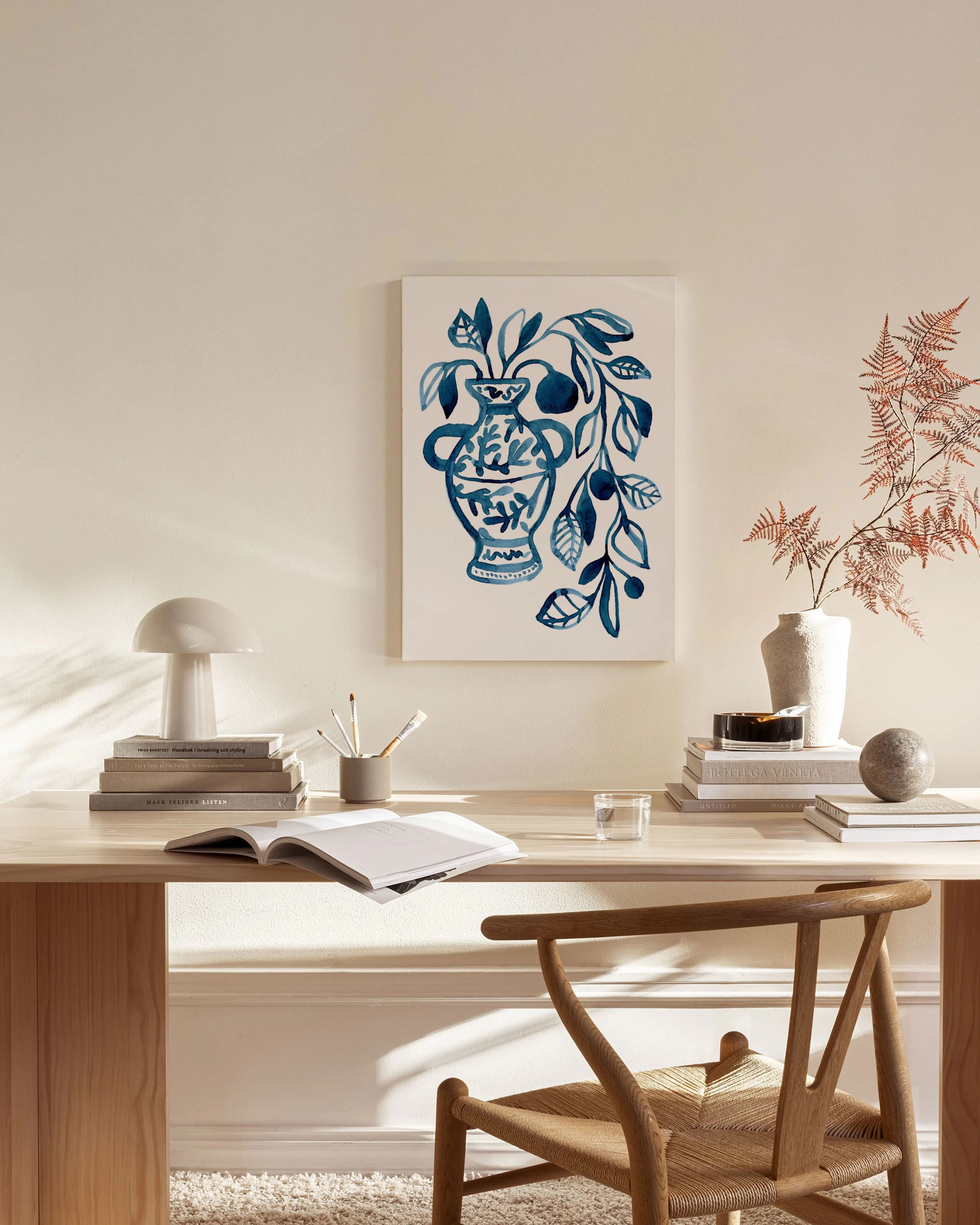 Lienzo de jarrón azul con motivos florales y botánicos, colgado en una sala de estar moderna con muebles de madera clara.
