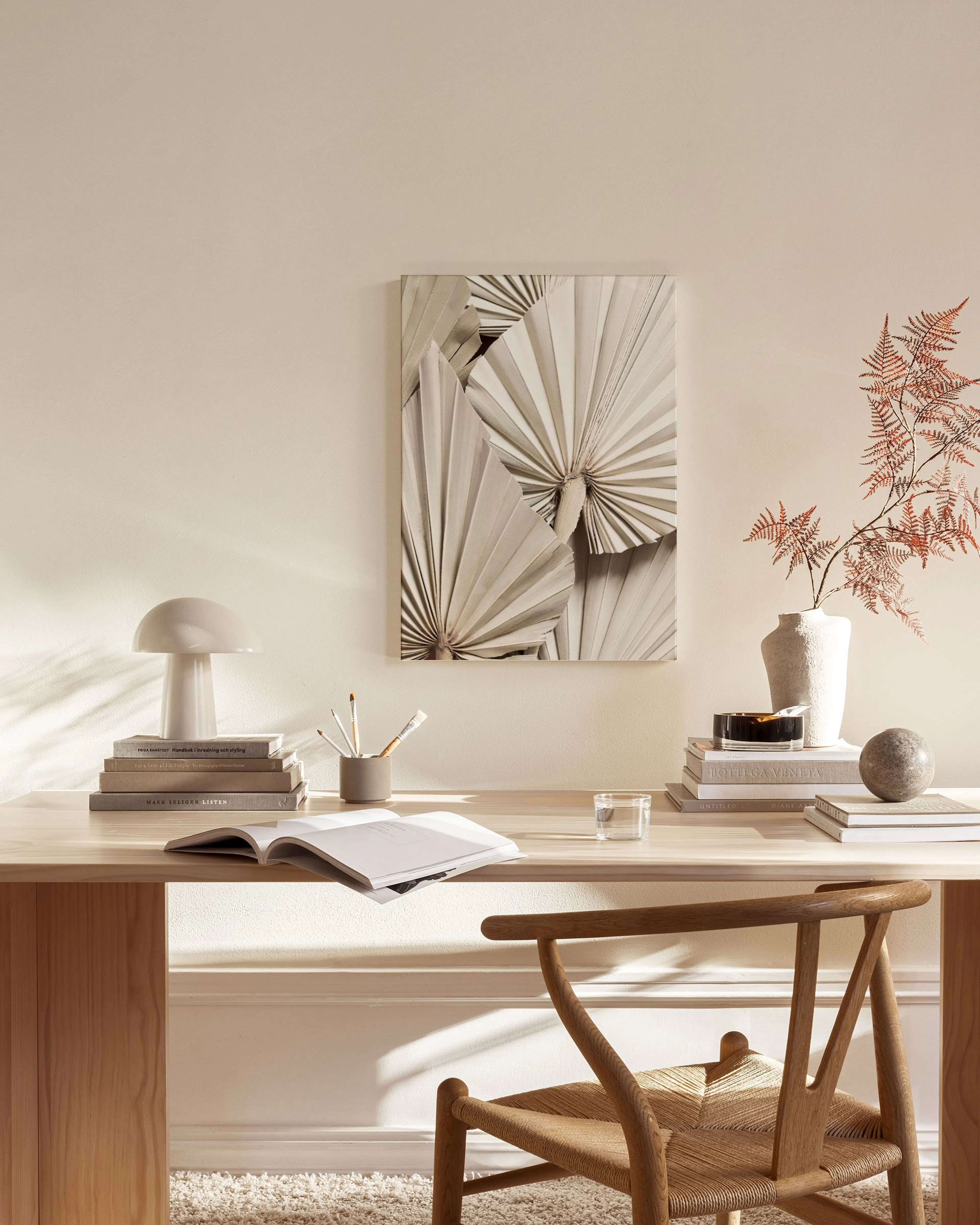 Lerretsbilde med beige palmefolder som et blikkfang i et lyst, moderne stuemiljø.