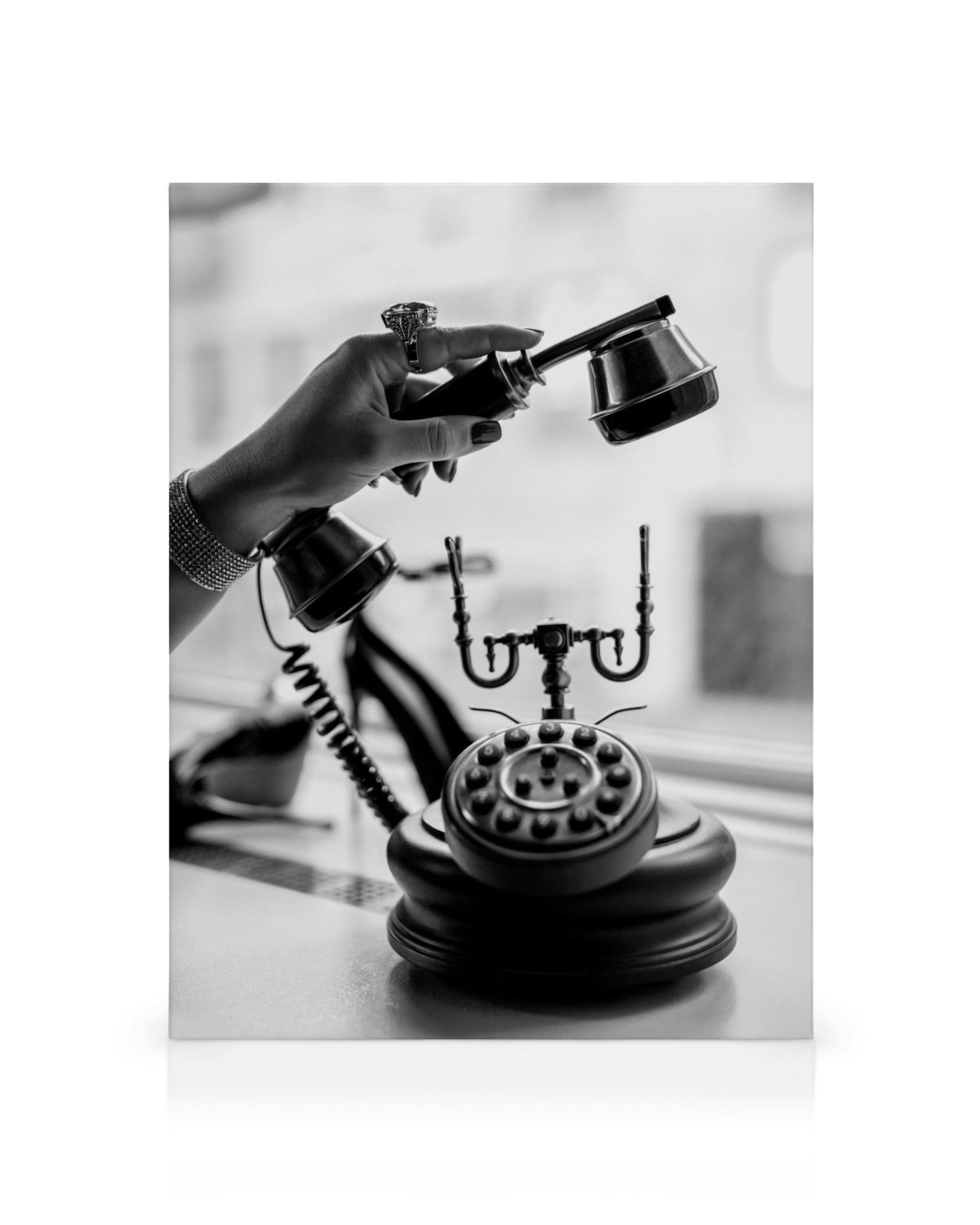 Black and white vintage rotary telephone with a womans hand holding the receiver, showcasing detailed antique design.