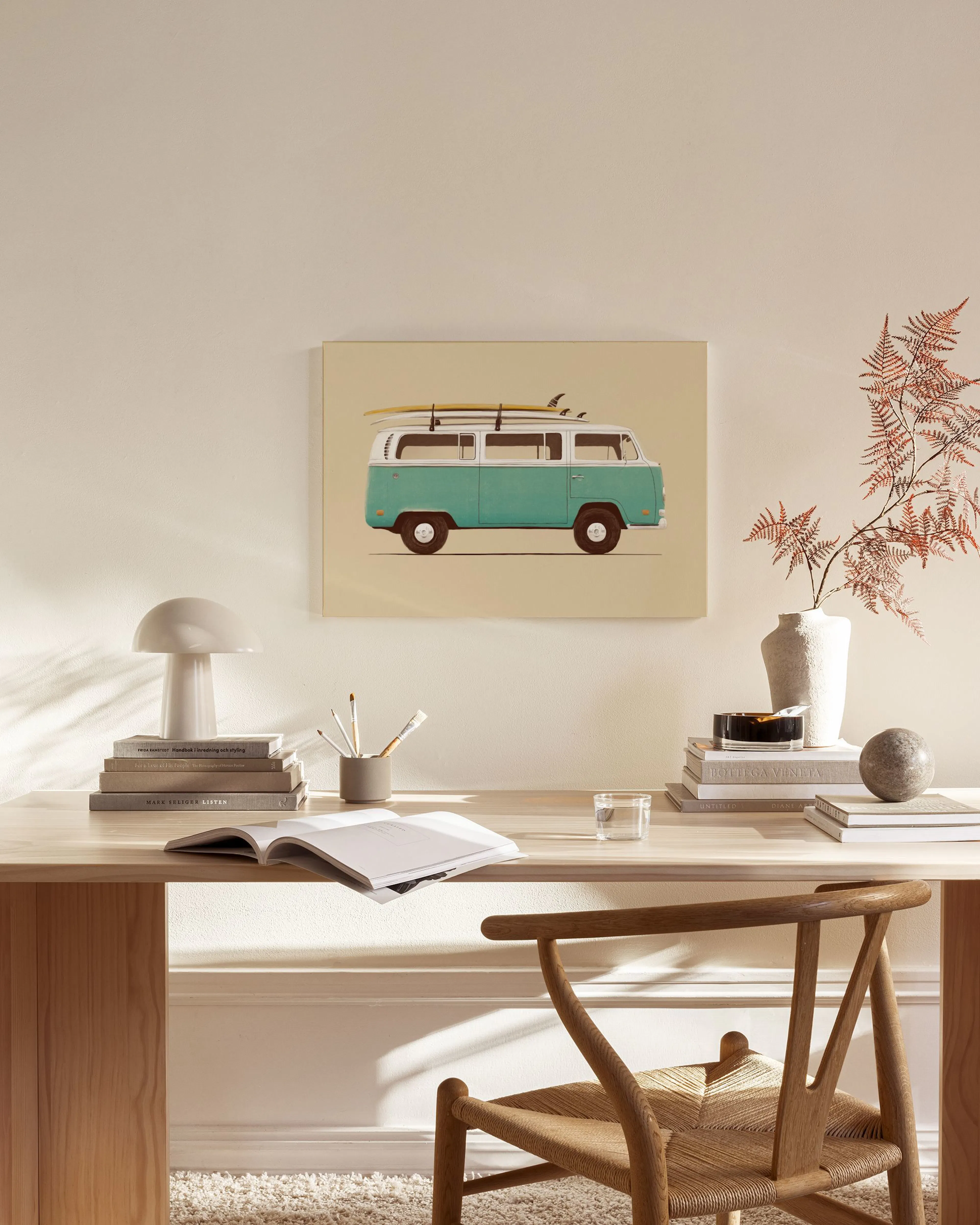 A canvas print of a teal and white vintage surf van with surfboards on top, hanging above a wooden console table in a minimalist