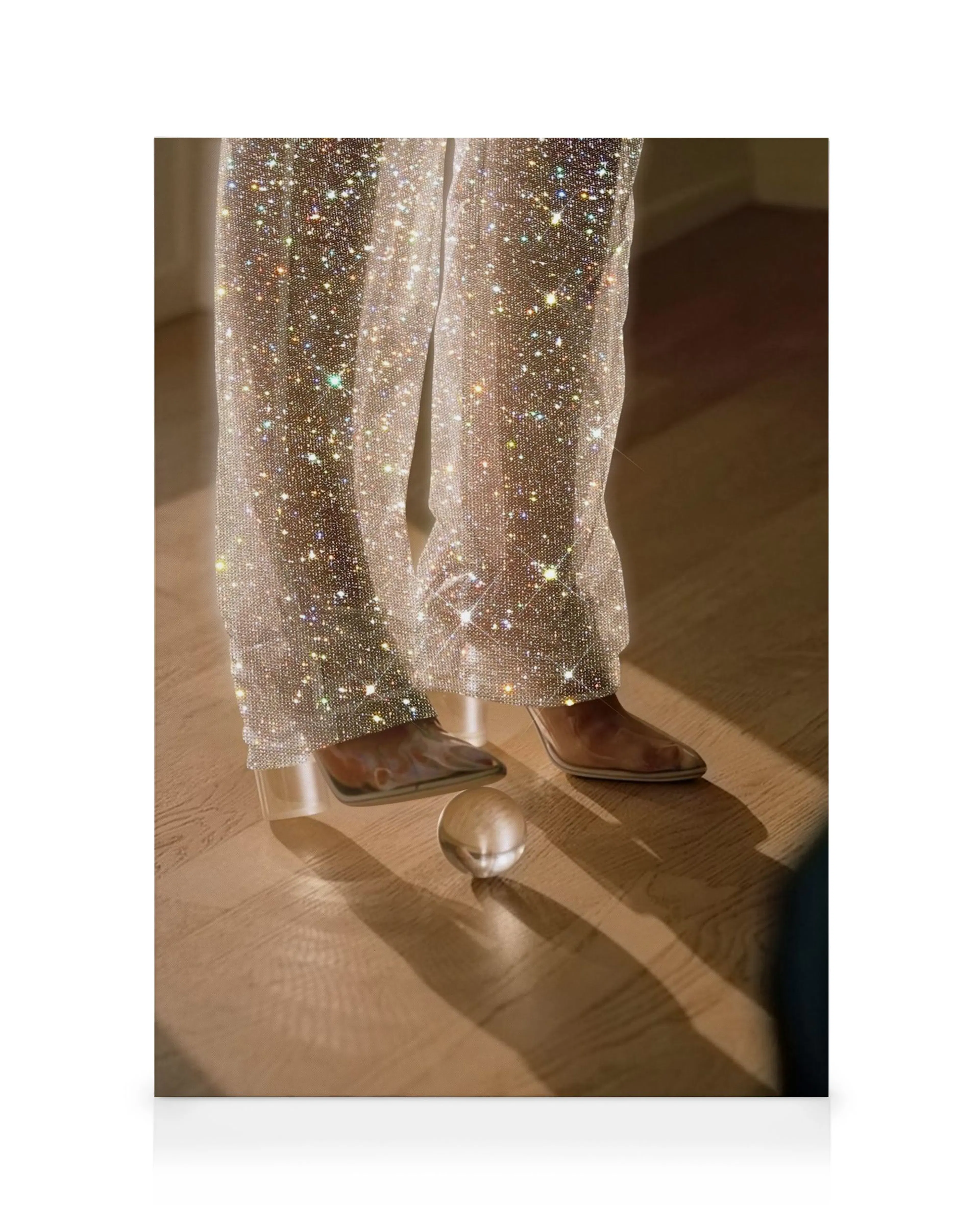 Sparkling silver glitter pants and brown boots on a wooden floor with a glass sphere, reflecting light on this canvas print.