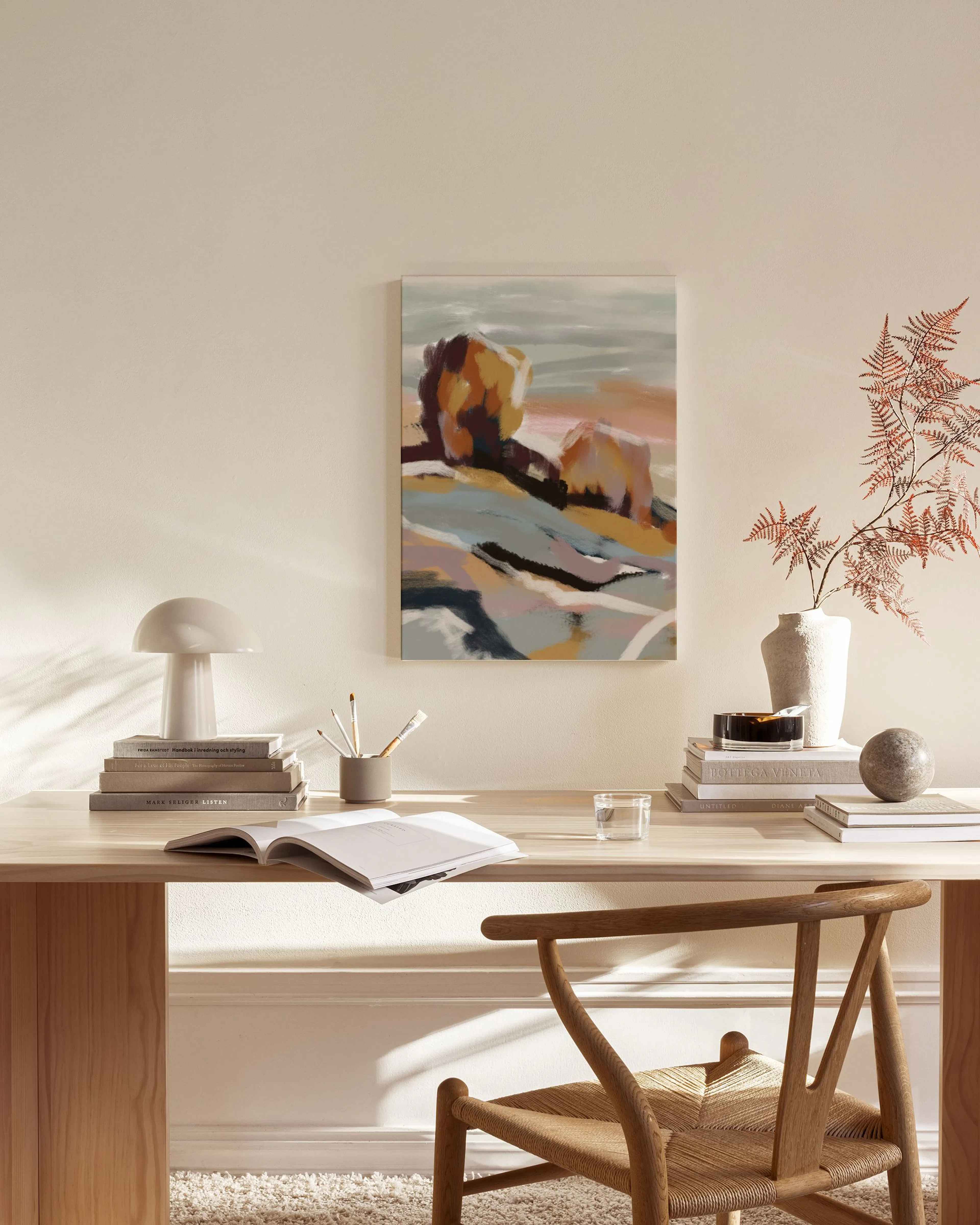 Abstract landscape print with warm orange and cool blue tones, hanging in a minimalist living room.