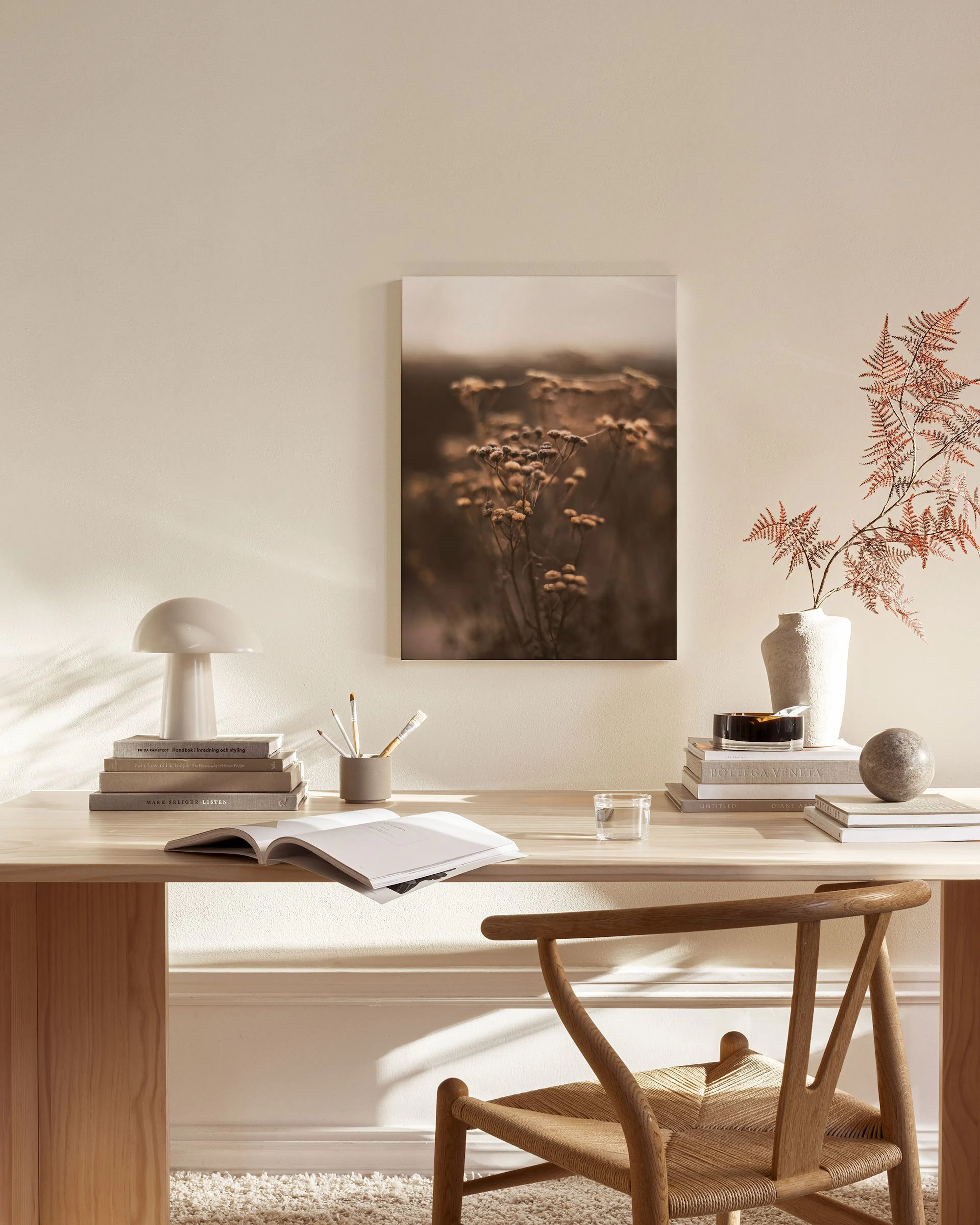 A canvas print of dried wildflowers in a field, displayed in a neutral-toned living room above a wooden console.