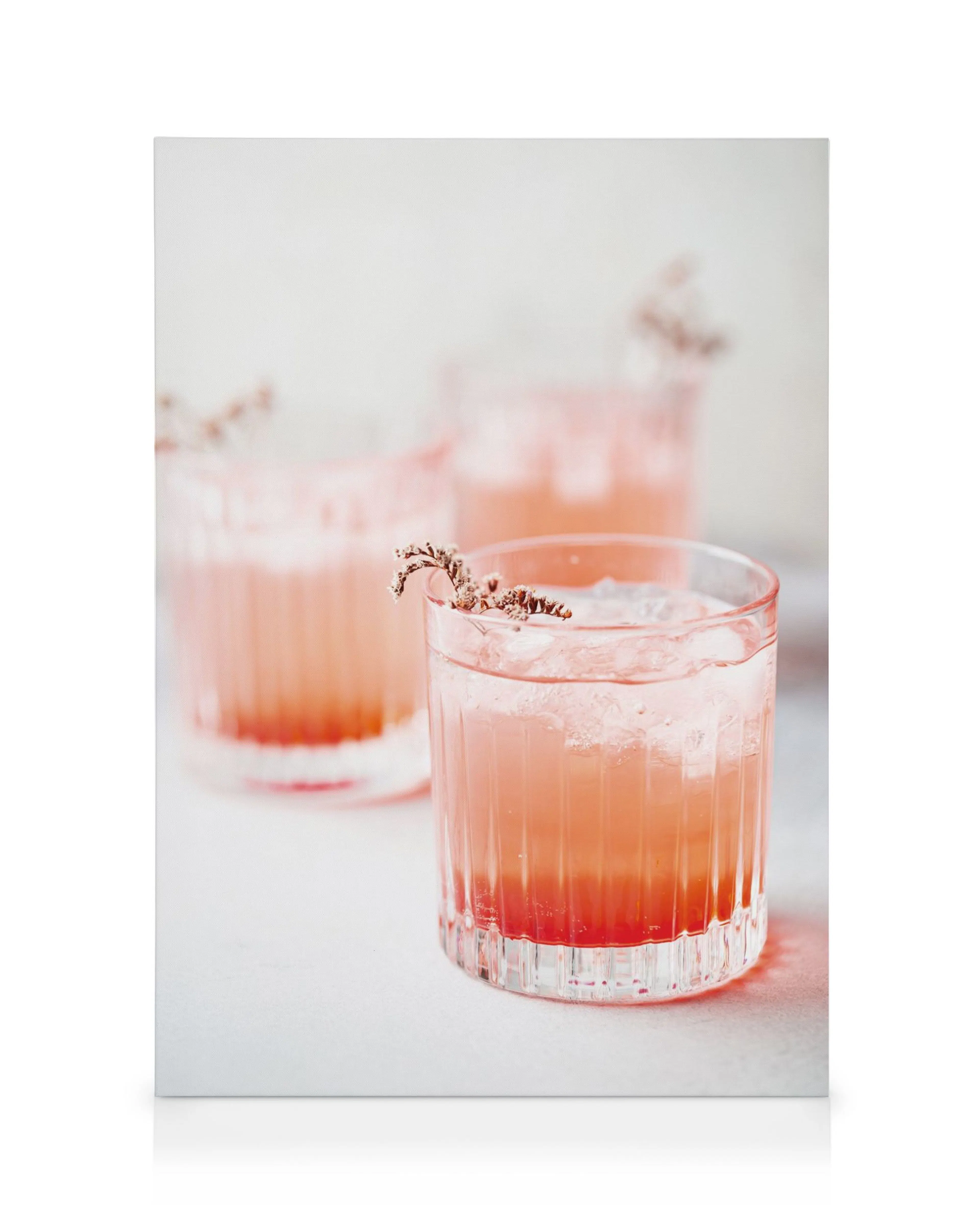 Tre rosa cocktailar med is och fruktgarnering i klara glas på en ljus bakgrund, perfekt för kök eller matsal.