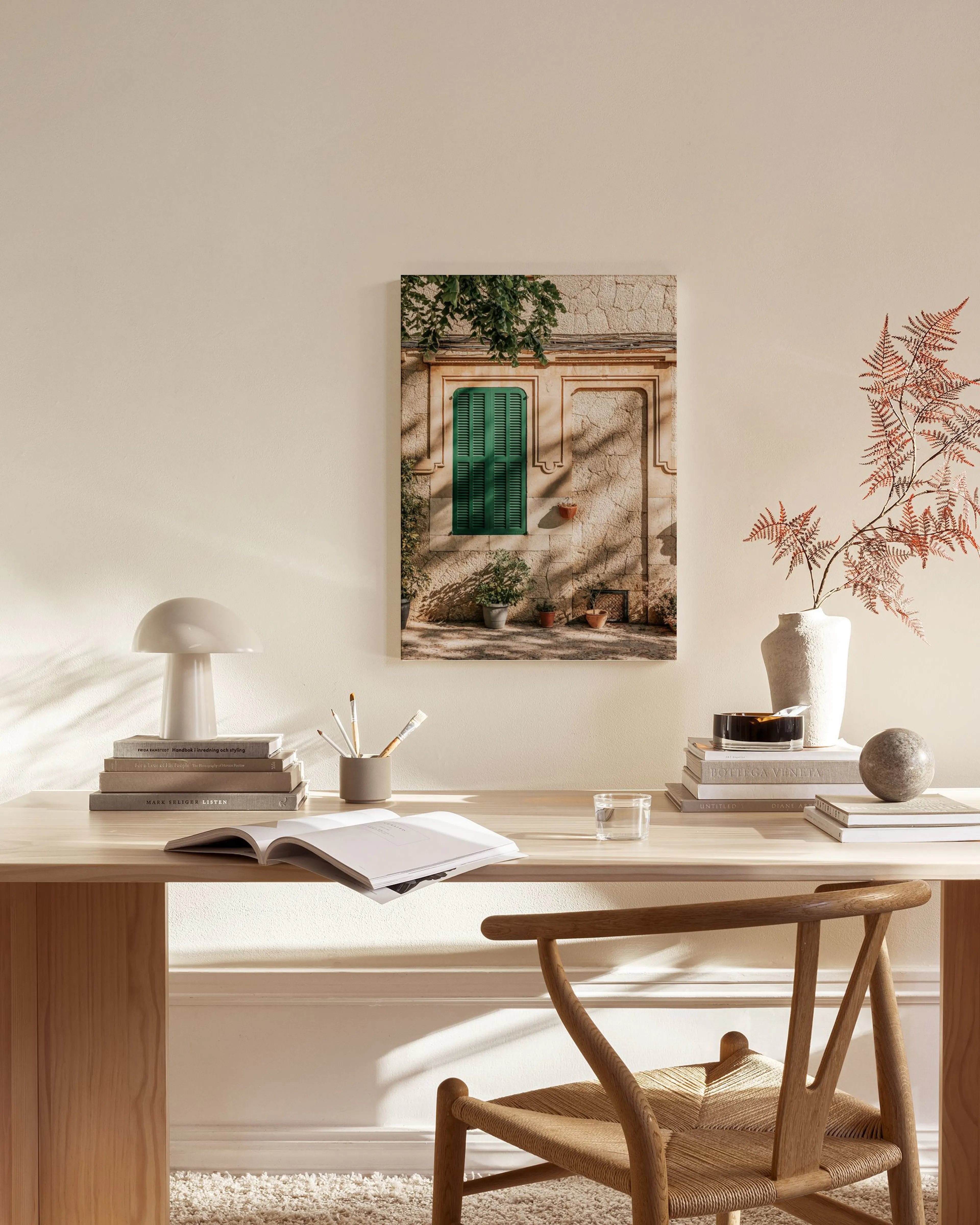 Toile murale dune façade méditerranéenne en pierre avec un volet vert, accrochée dans un salon moderne.