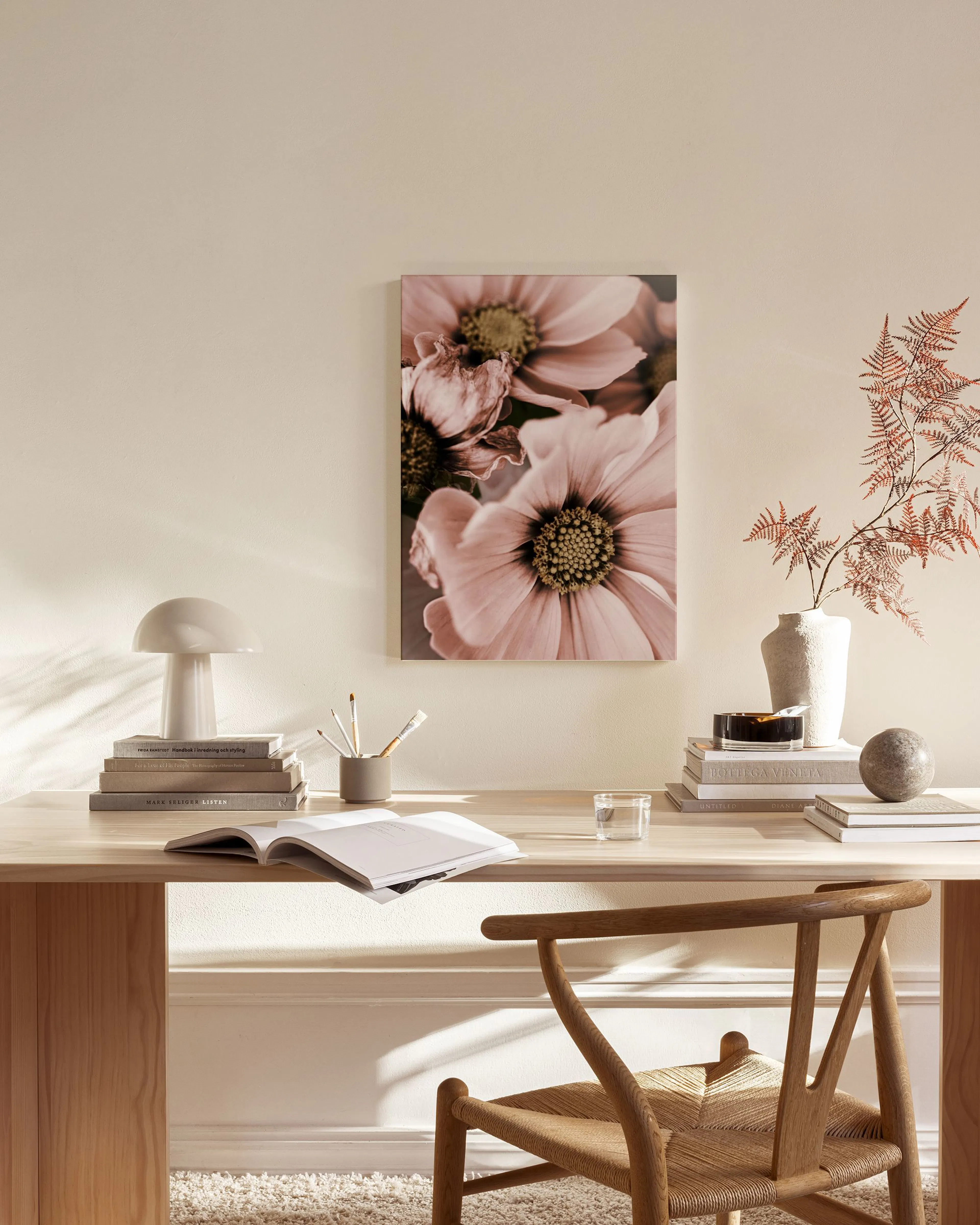 Stampa su tela con fiori rosa e centri gialli, appesa sopra una panca in legno in un soggiorno moderno.