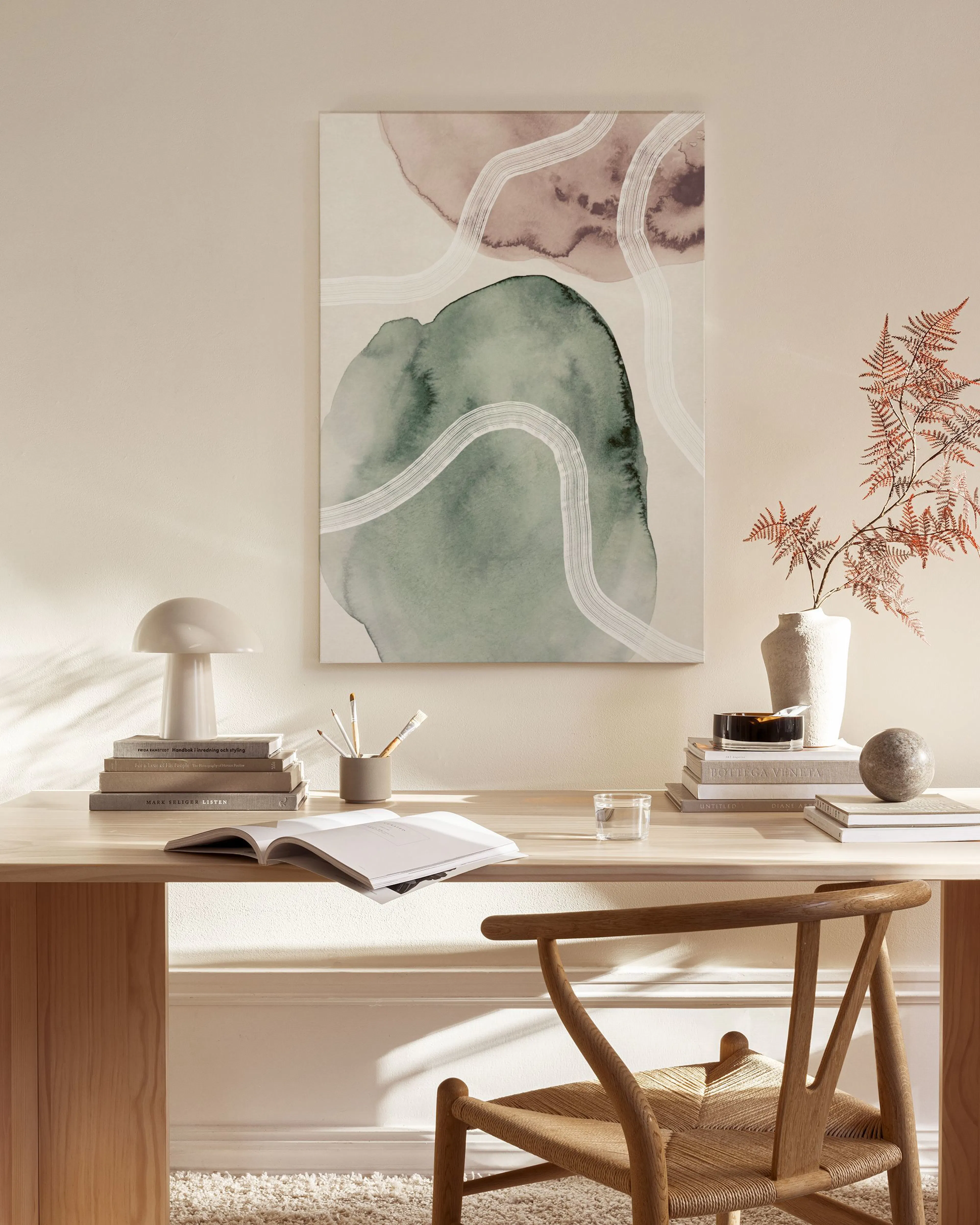Abstract watercolor canvas print with green and peach organic shapes, and white flowing lines, hanging in a minimalist living ro