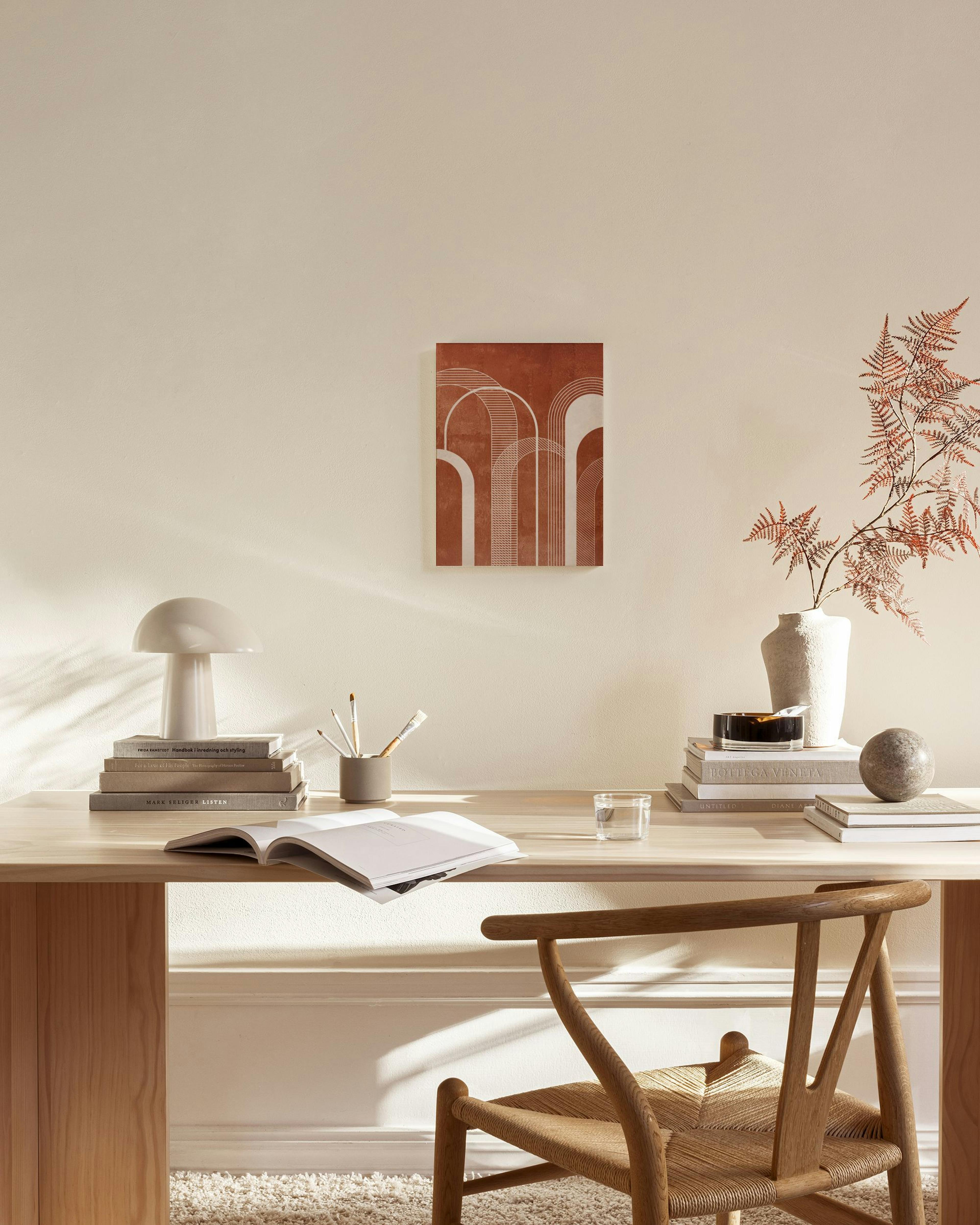 Toile murale marron-rougeâtre avec motifs darches blanches, suspendue dans un salon moderne aux tons neutres.