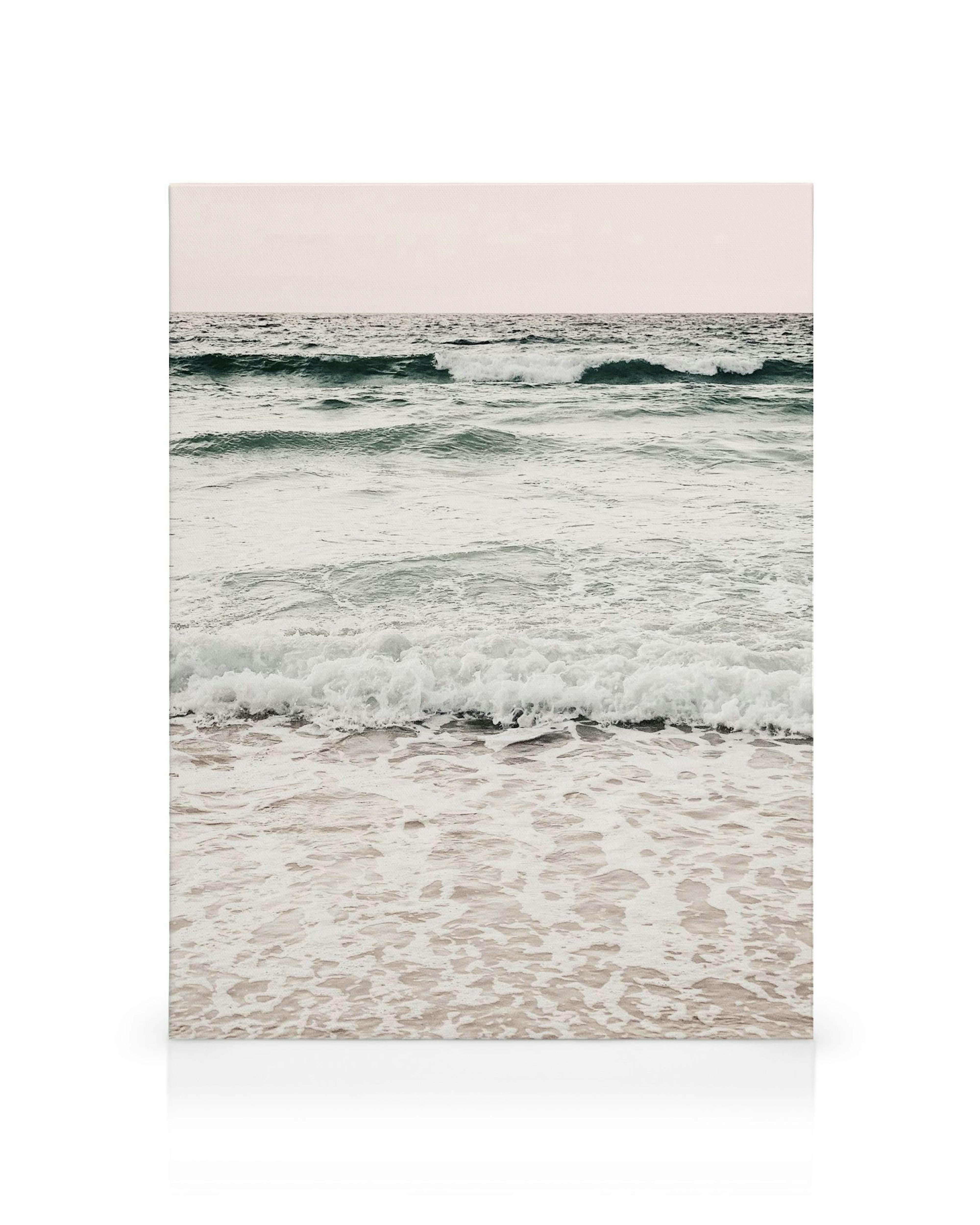 Ocean waves crashing on the shore with white foam and blue-green water under a pale sky canvas art