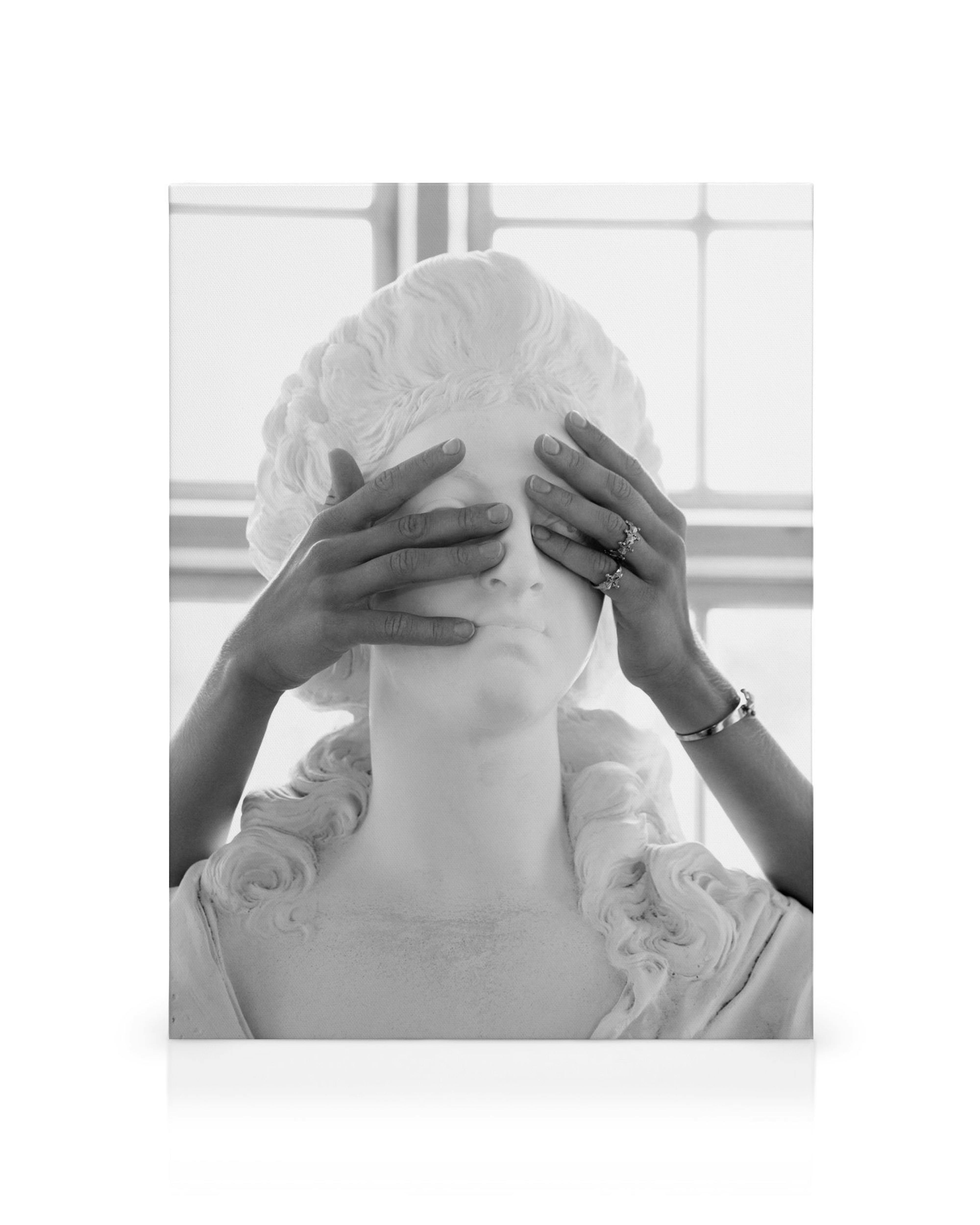 Black and white canvas print of hands covering a marble statues eyes against a grid window background.