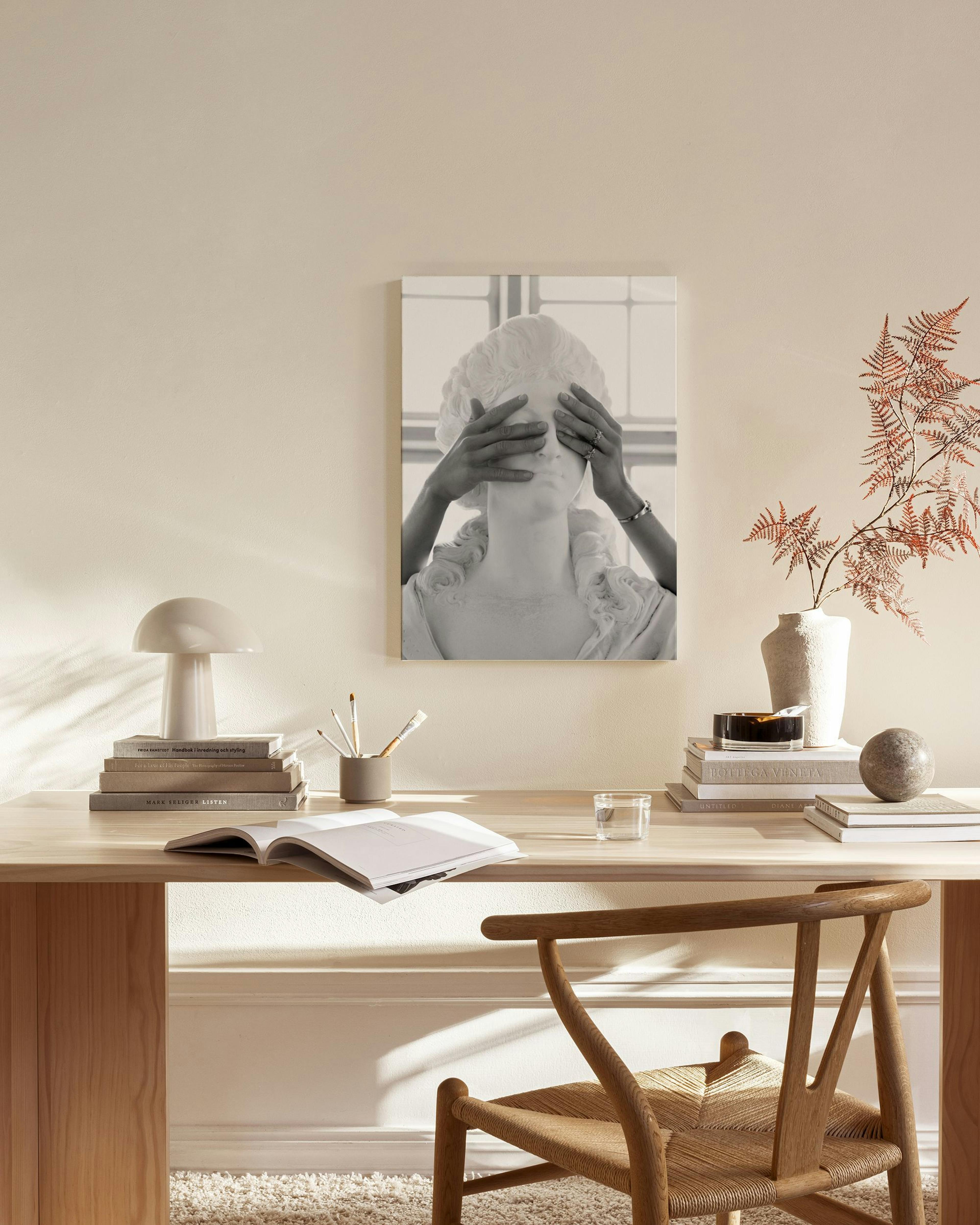 A black and white canvas print depicting a statue with hands covering its eyes, hanging in a minimalist living room.