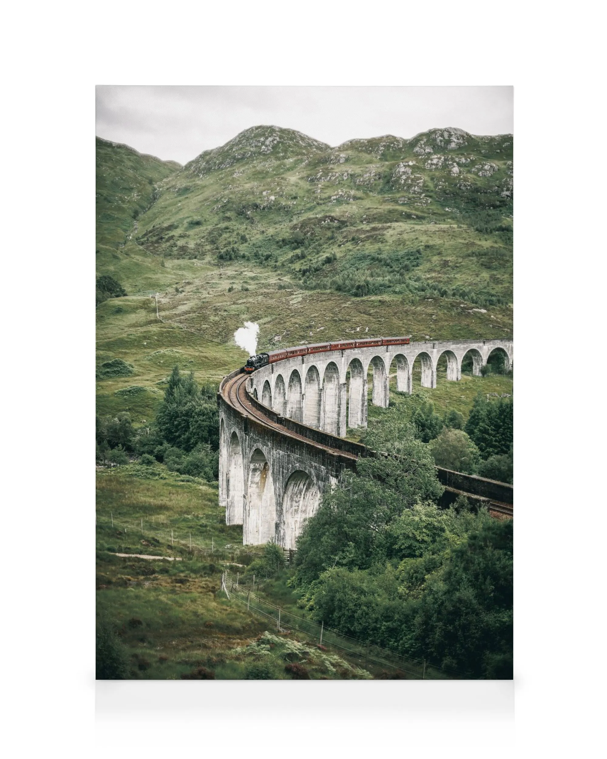 Glenfinnan Viaduct with a red and black steam train crossing a stone arch bridge in green hills.