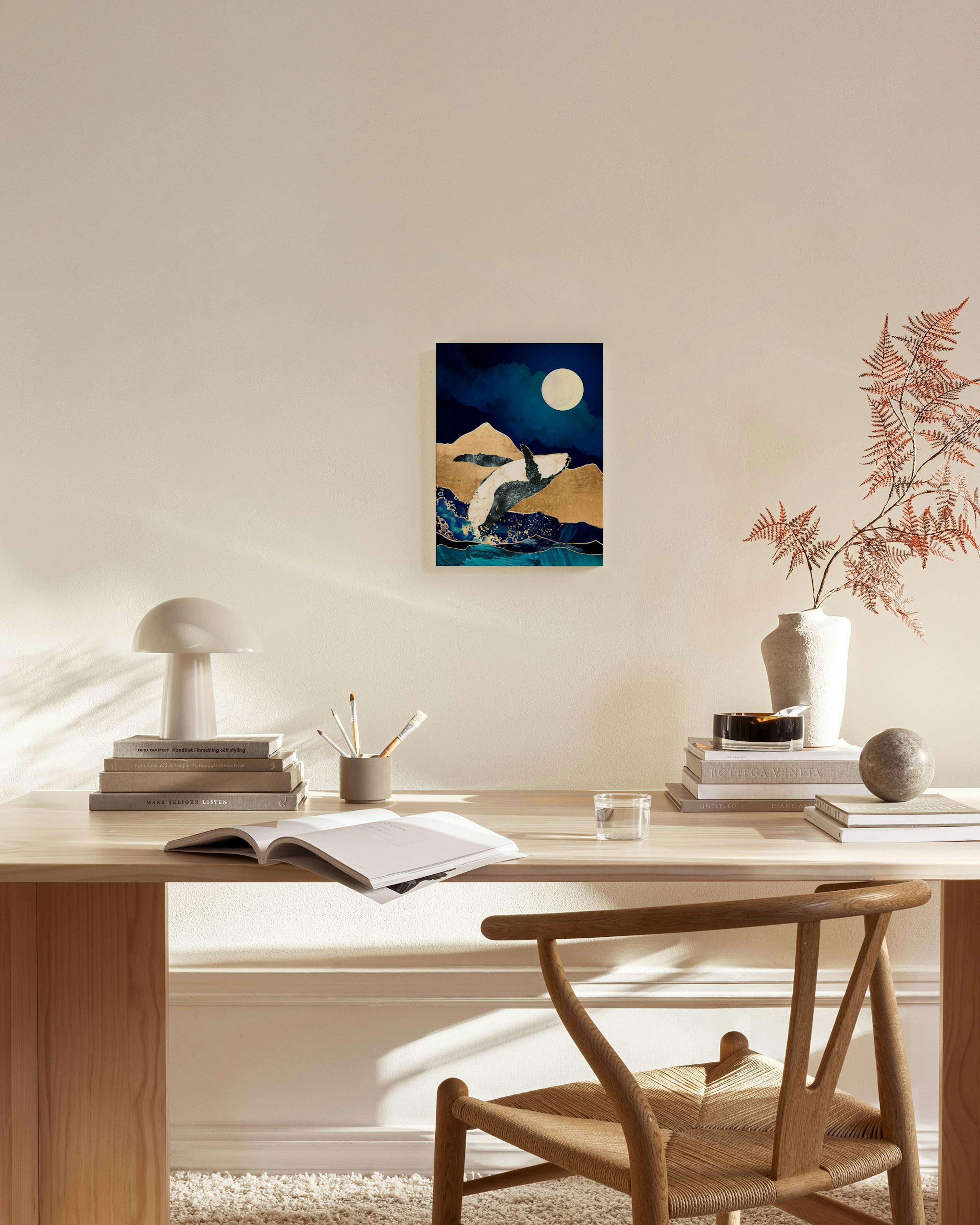 Toile dune baleine blanche sautant des vagues sous une pleine lune sur des montagnes dorées, accrochée dans un salon moderne.