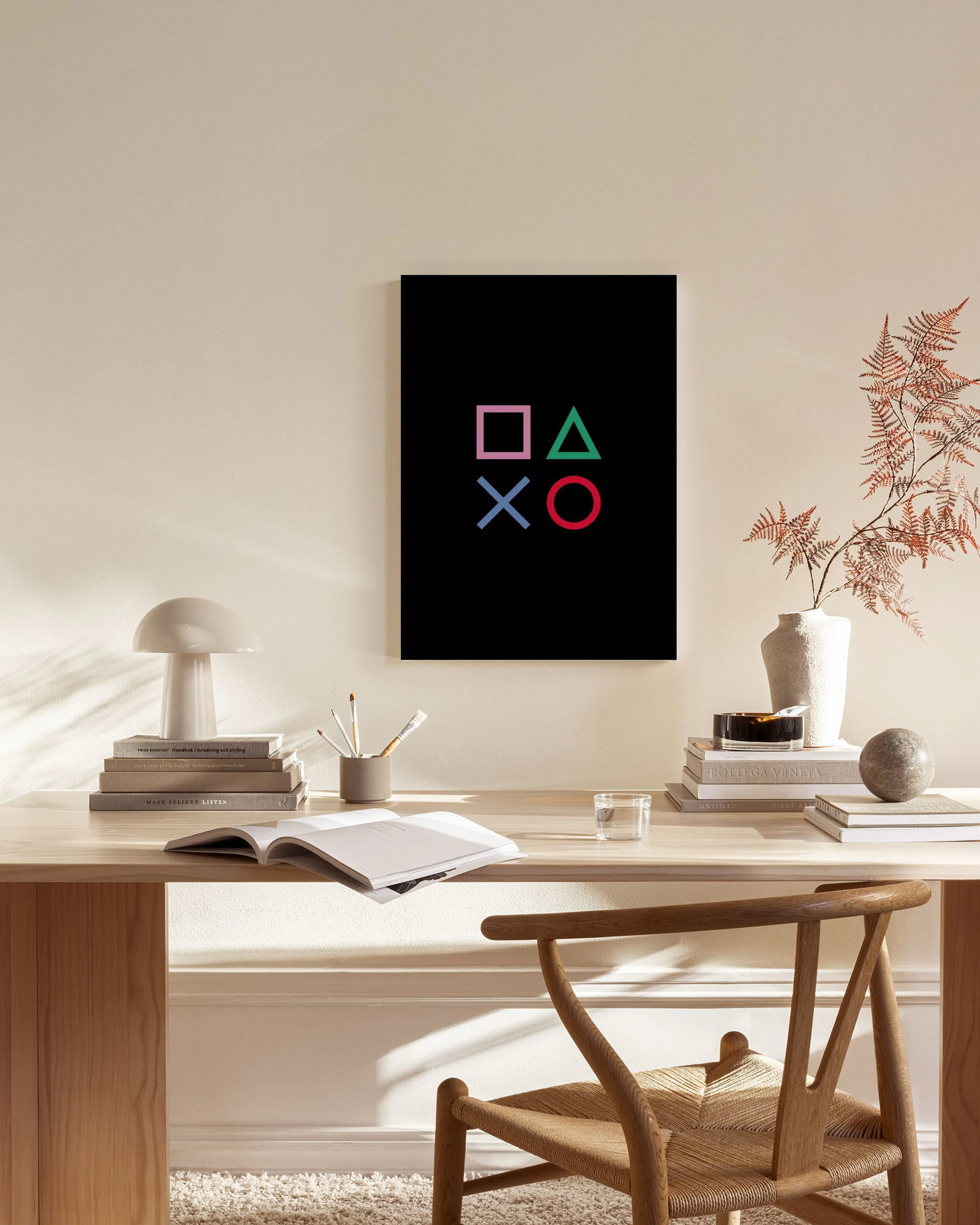 Leinwandbild mit rosa Quadrat, grünem Dreieck, blauem X und rotem Kreis auf Schwarz, über einem Sideboard in einem Wohnzimmer.